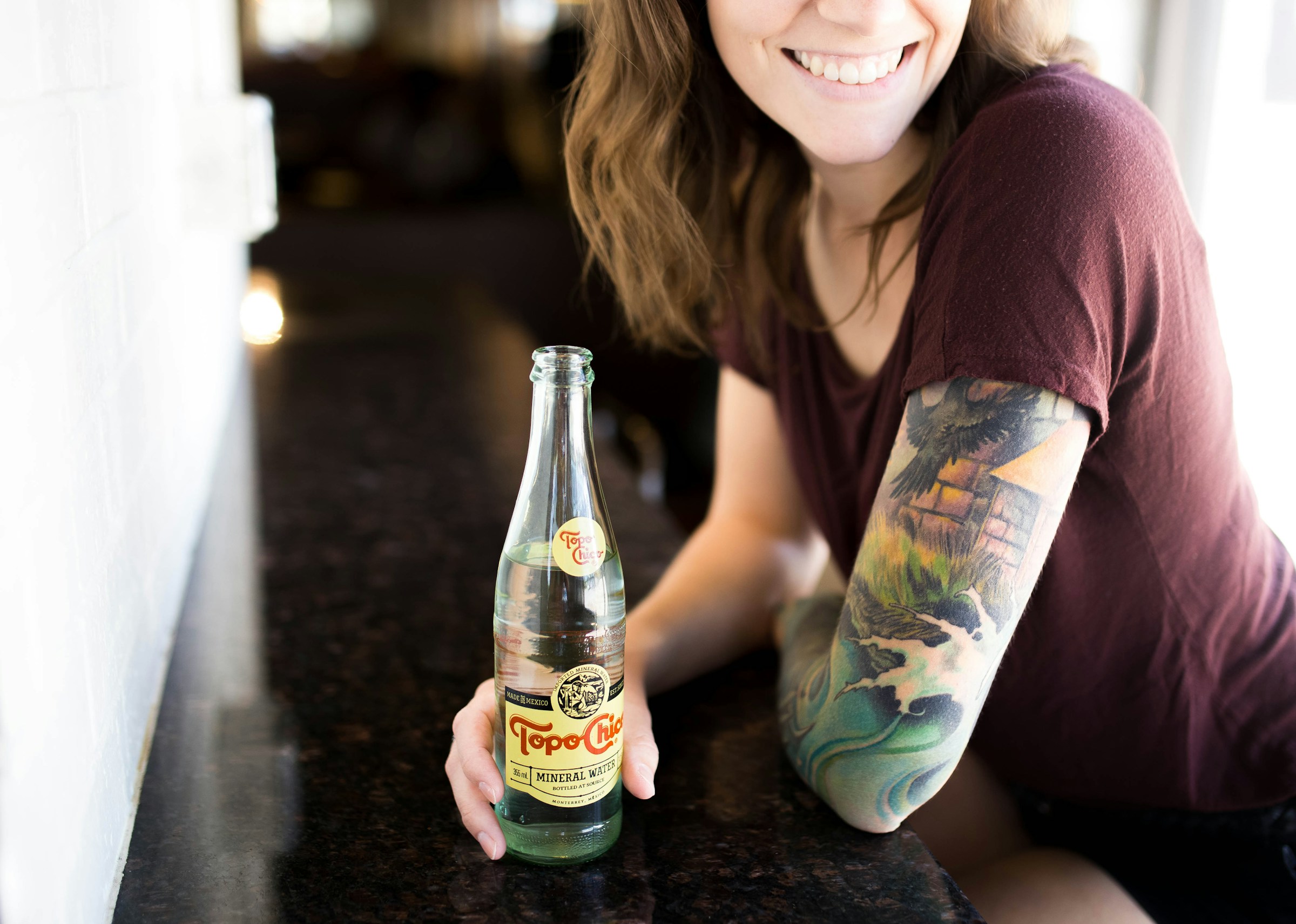 A woman with a tattoo holding a bottle | Source: Unsplash