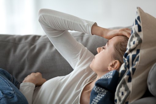 Jeune femme déprimée allongée sur le canapé. | Photo : Getty Images