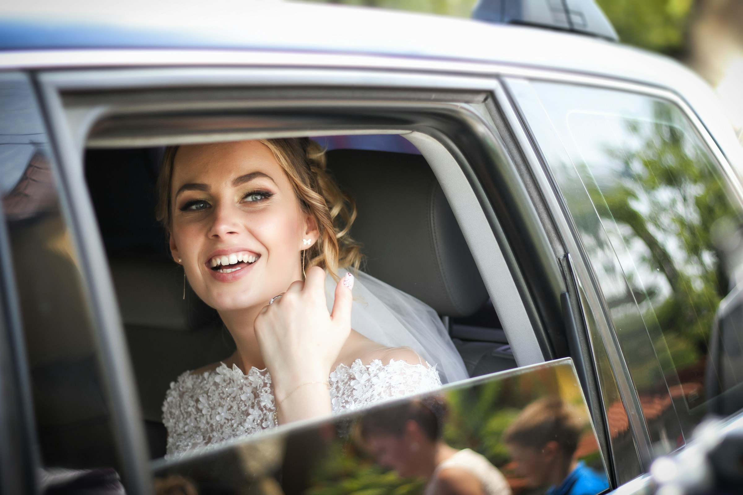 A bride in a car looking outside and smiling | Source: Unsplash