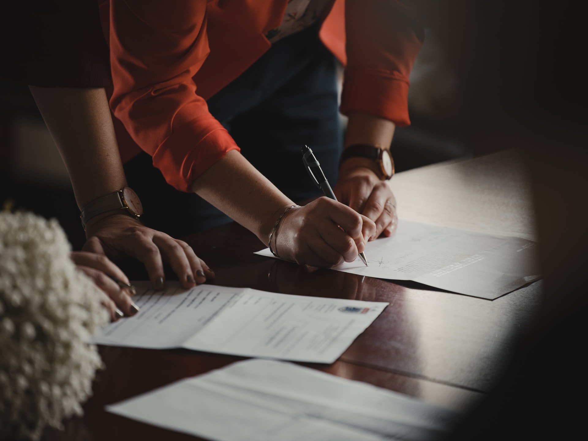 Close-up of man and woman signing papers. | Source: Unsplash