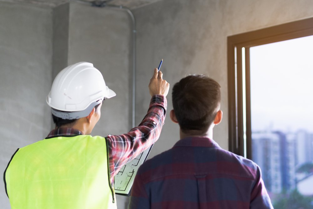 A Client and Contractor discussing plans to repair a building. | Photo: Getty Images.