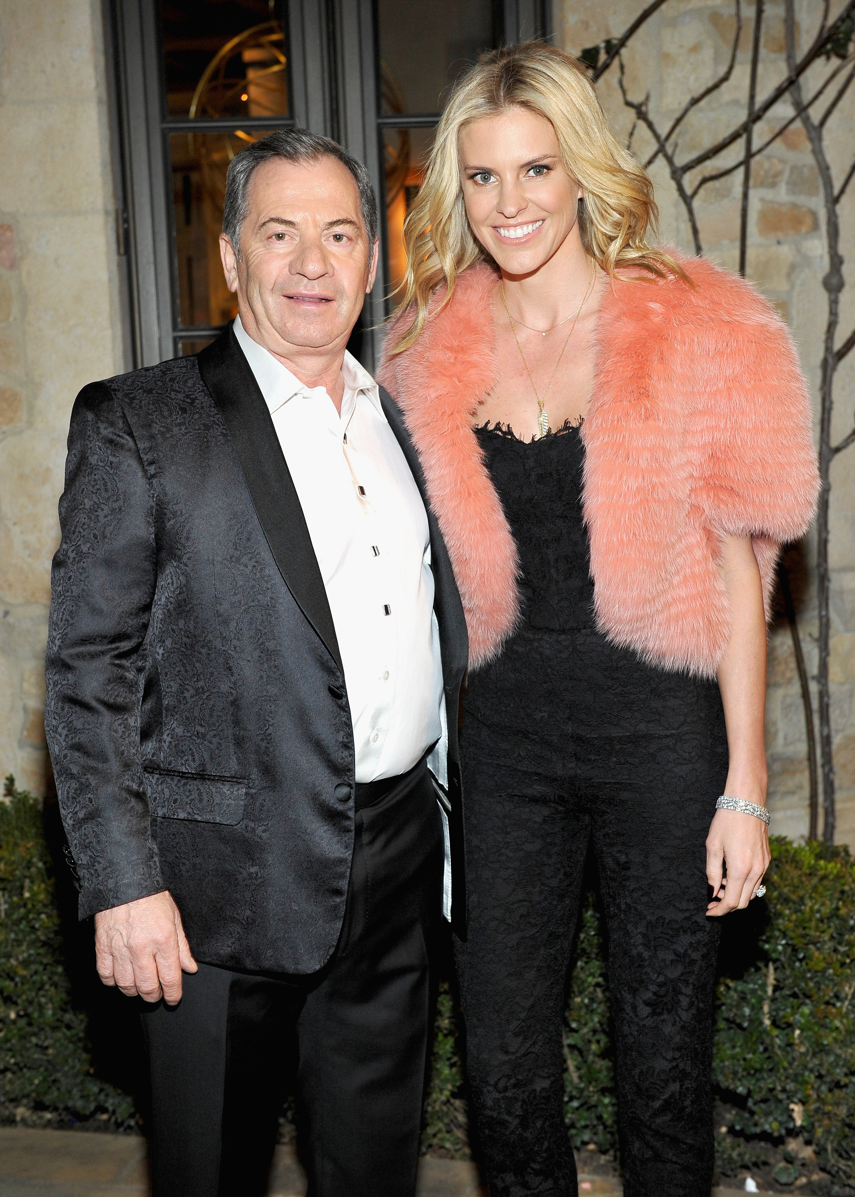 Alec Gores and Kelly Noonan Gores posed together at the PSLA Winter Gala, with the latter stealing the spotlight in a lace jumpsuit and bold pink fur shrug. The couple smiled for the cameras, exuding glamour and confidence at the upscale Beverly Hills event.