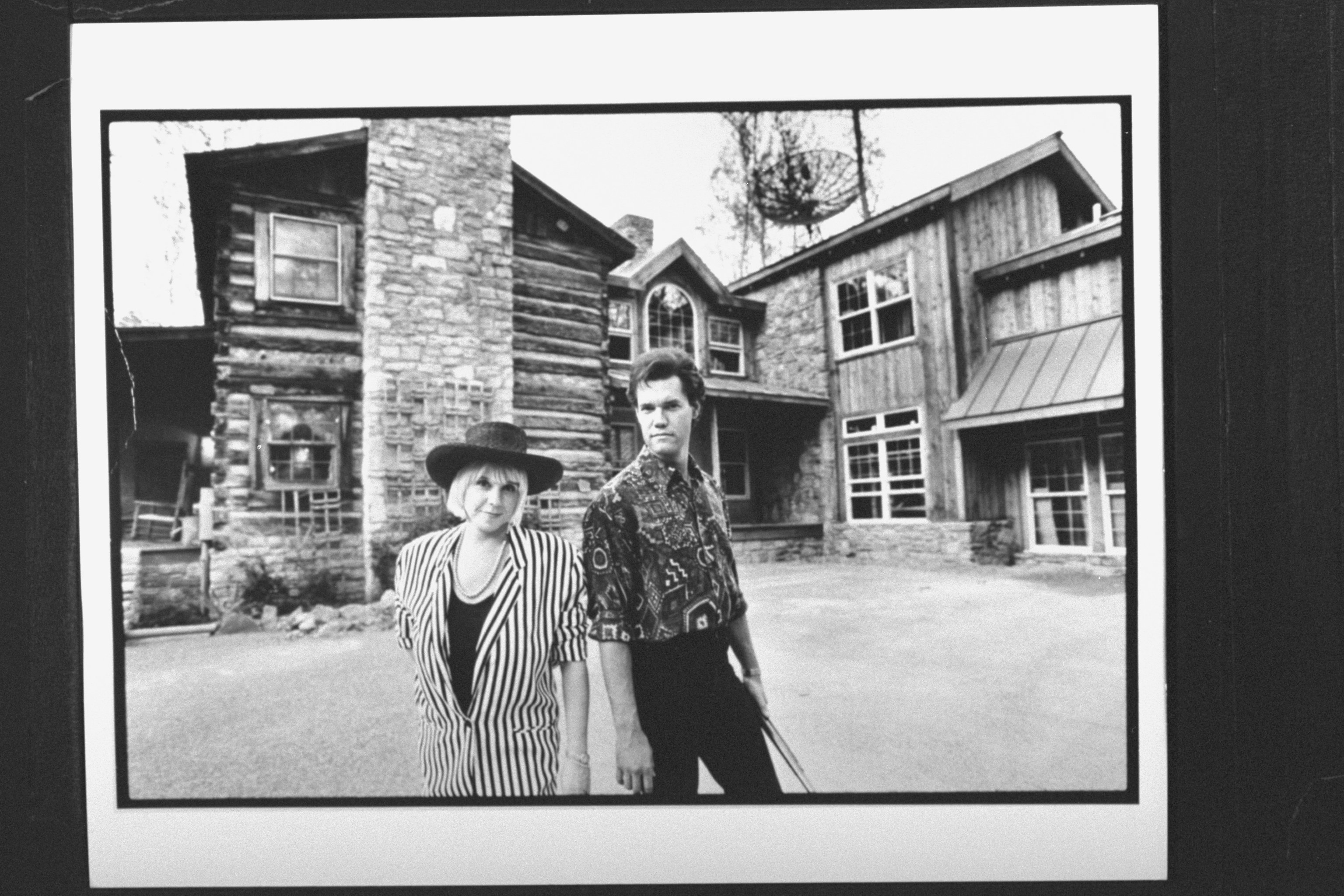 singer Randy Travis w. his manager wife Lib Hatcher, posing in front of their two-story log cabin. | Source: Getty Images