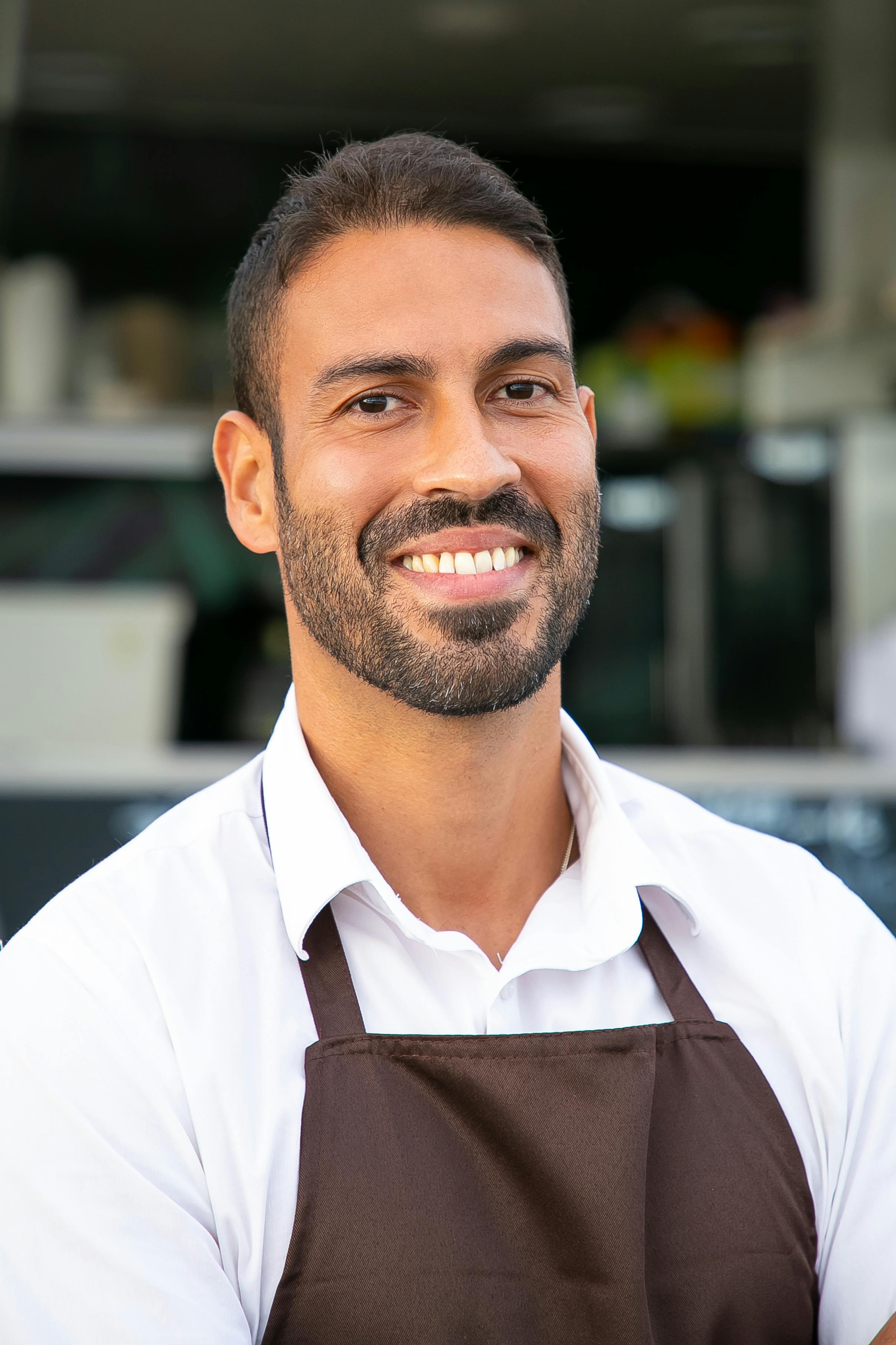 A happy and smiling man dressed in an apron | Source: Pexels