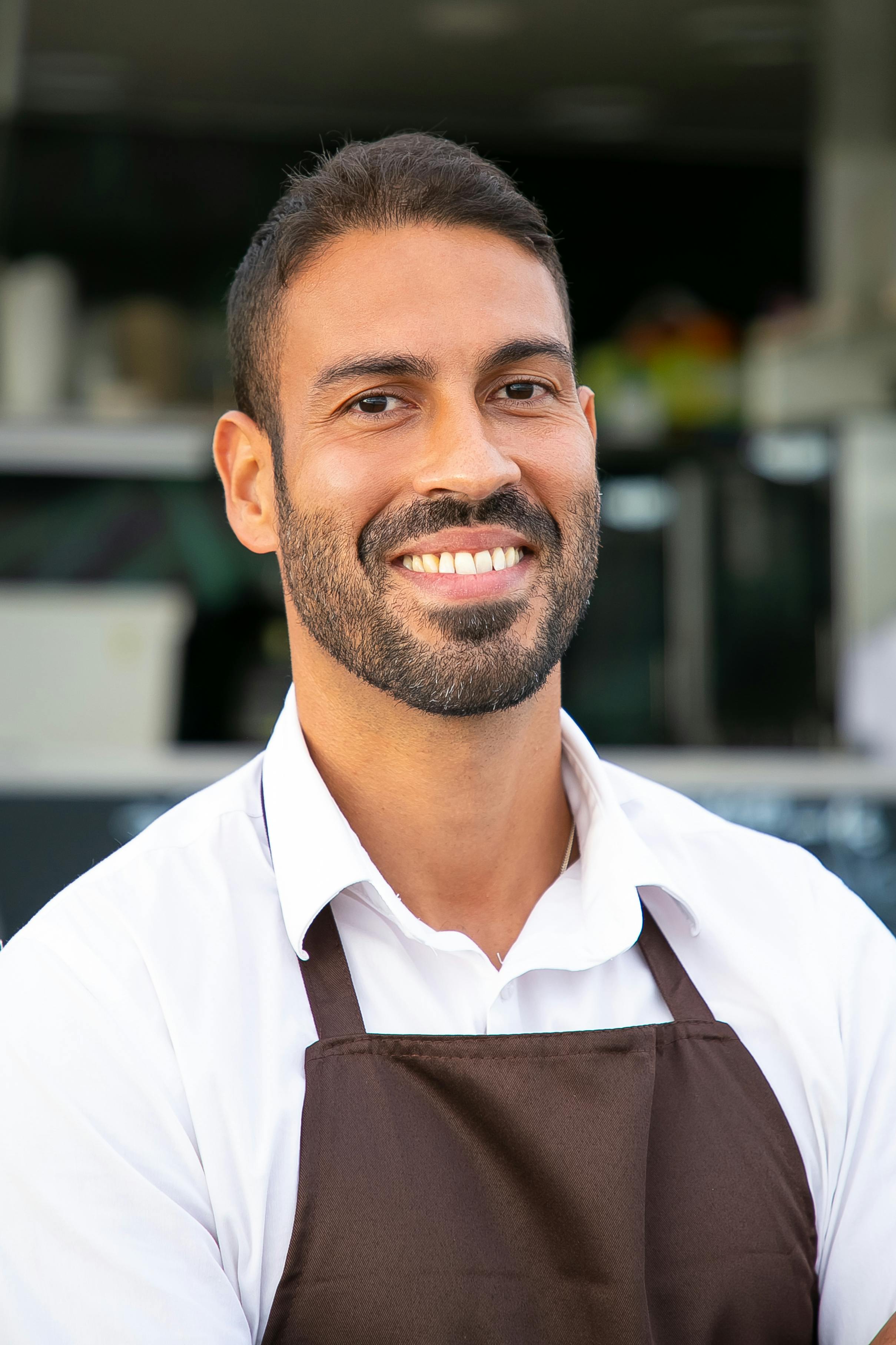 Un hombre feliz y sonriente vestido con un delantal | Fuente: Pexels