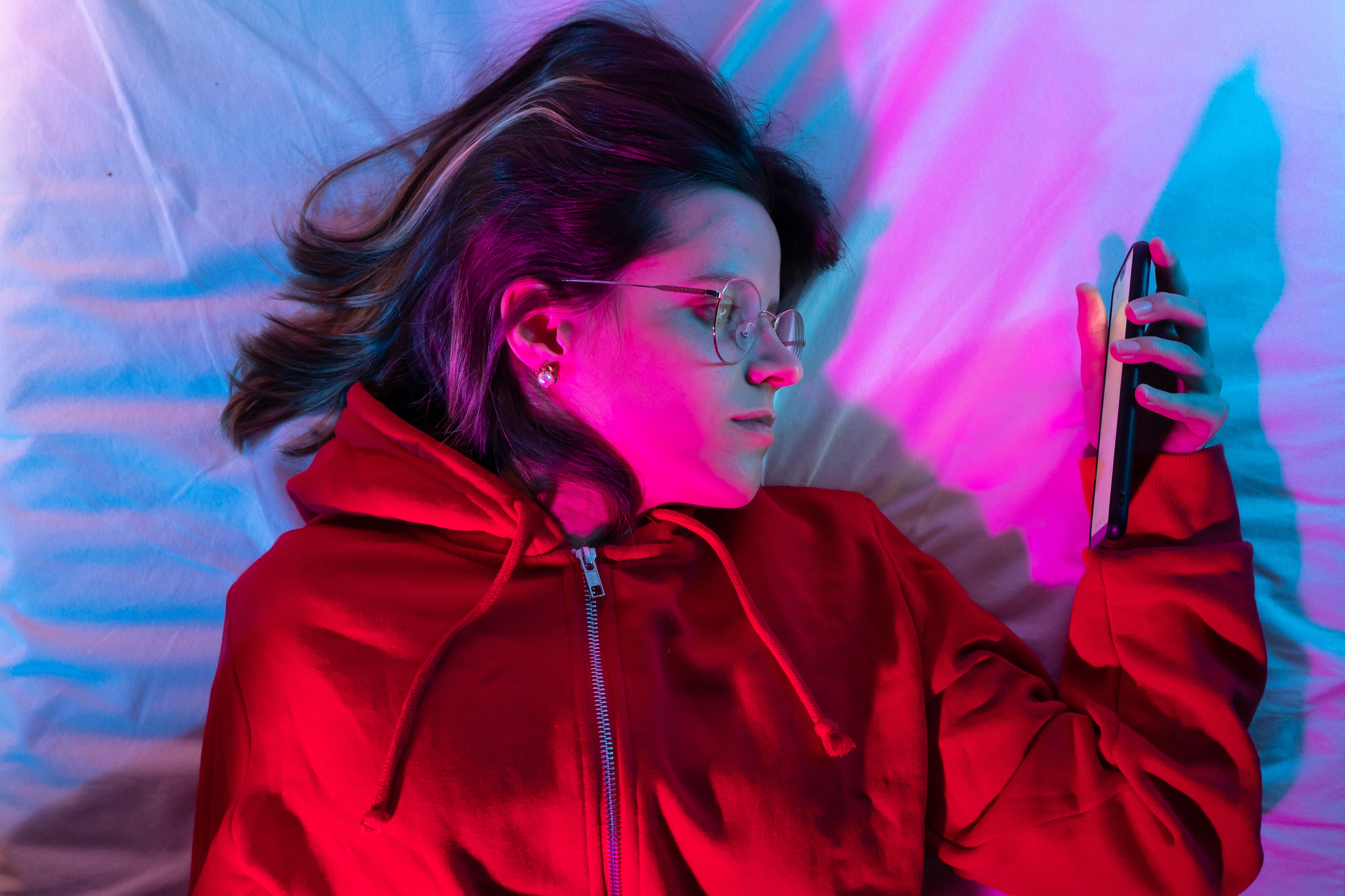 Young girl looking her smart phone doom scrolling on bed in the middle of the night | Source: Shutterstock.com