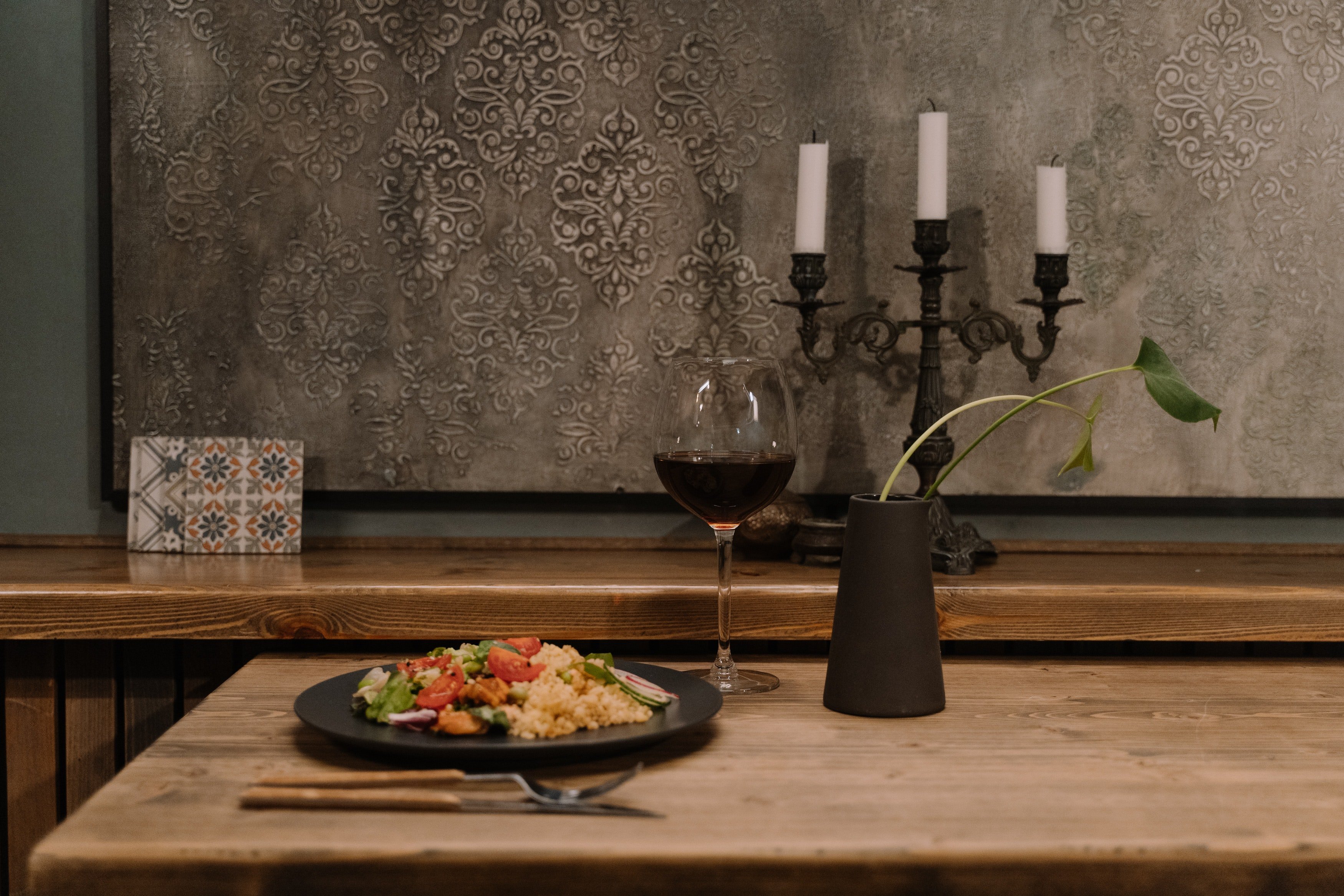 Plato de comida servido junto a una copa de vino. | Foto: Pexels