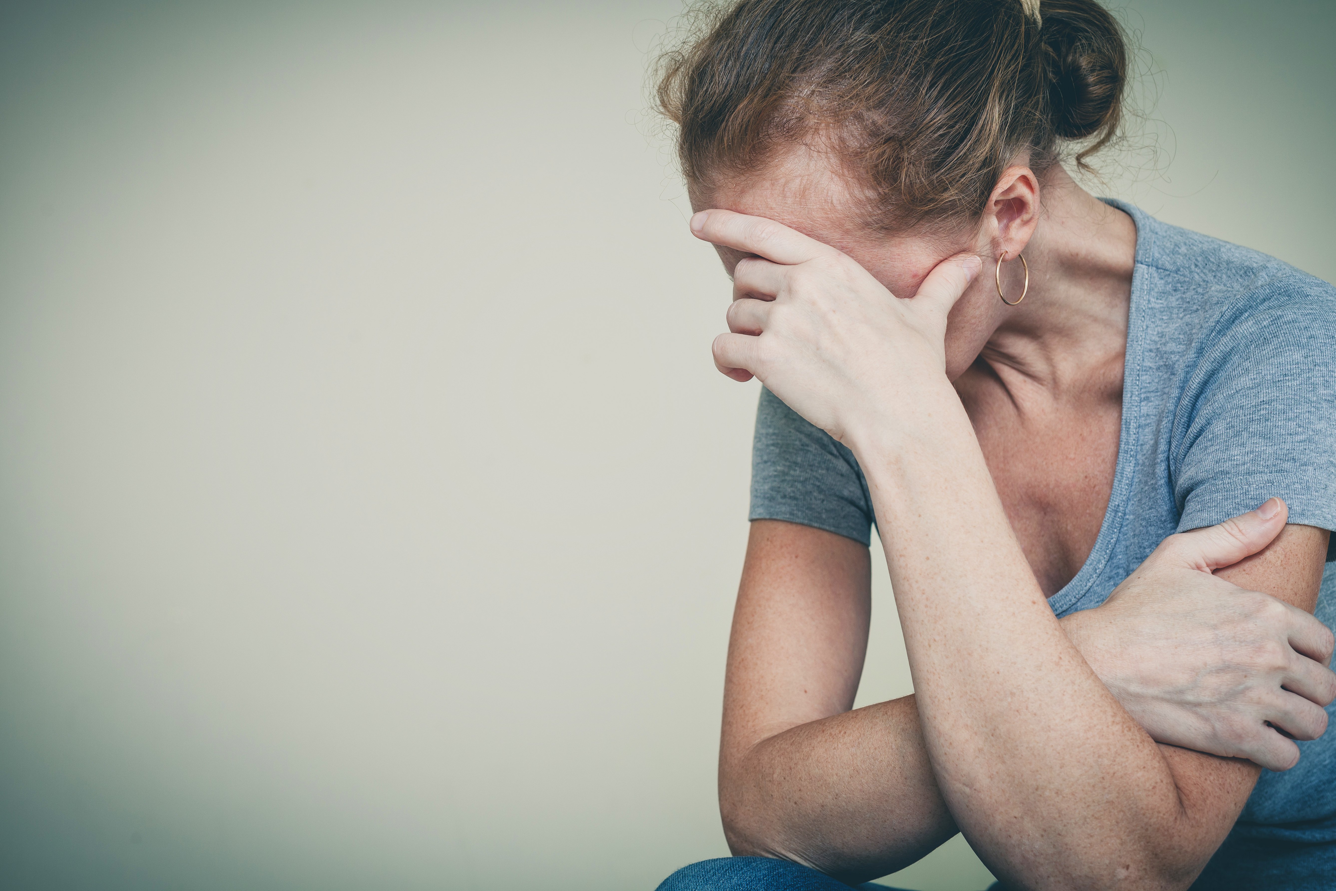 Mujer agobiada esconde rostro en su mano. | Fuente: Shutterstock Mujer agobiada esconde rostro en su mano. | Fuente: Shutterstock
