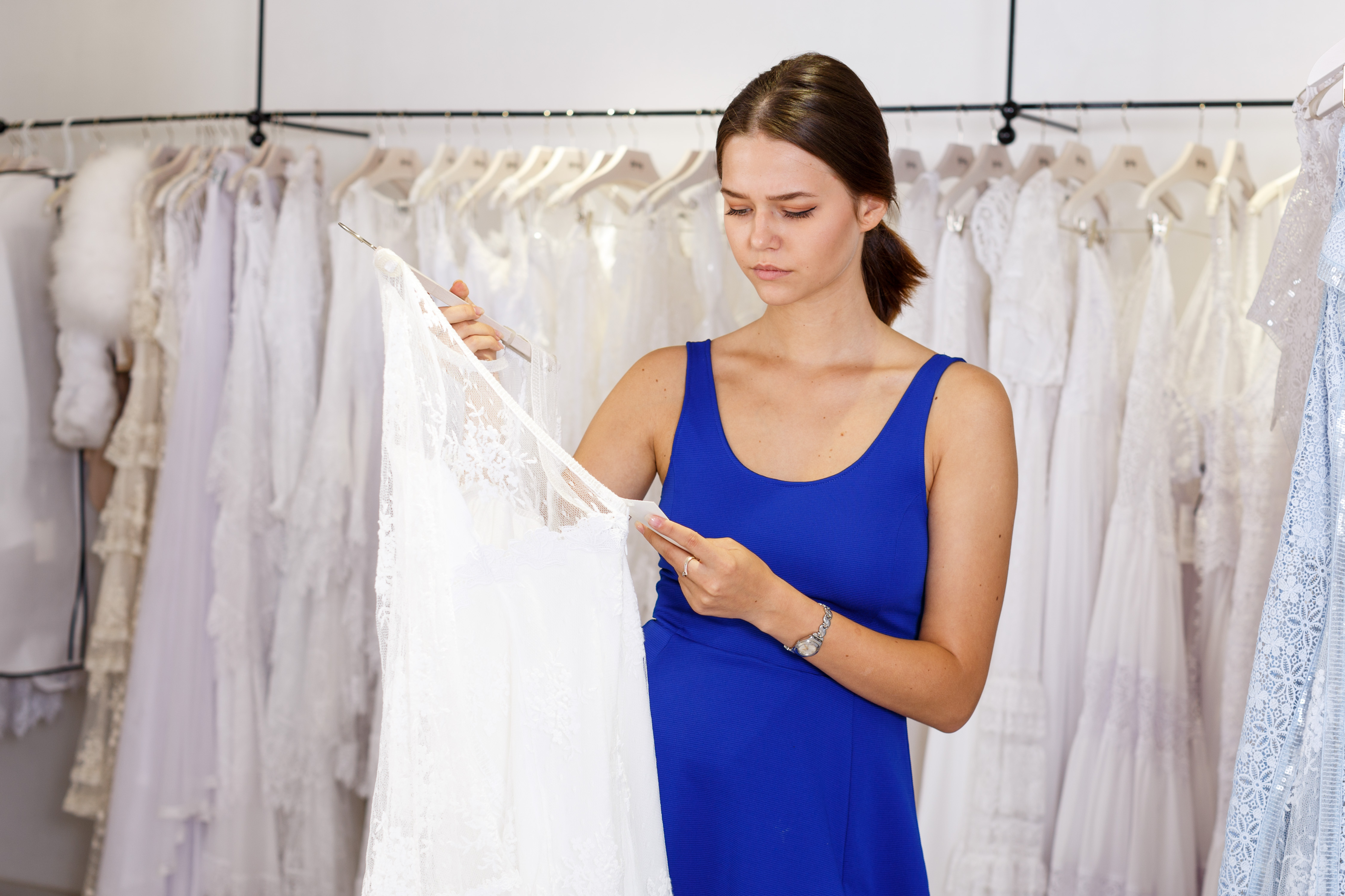 A woman looking sad as she holds a wedding dress | Source: Shutterstock