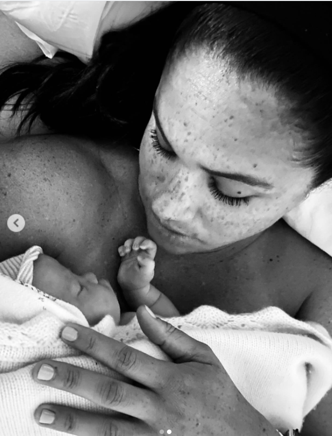 Meghan Markle gazes affectionately at newborn Princess Lilibet in an intimate black-and-white photograph capturing the earliest days of motherhood. | Source: Instagram/meghan