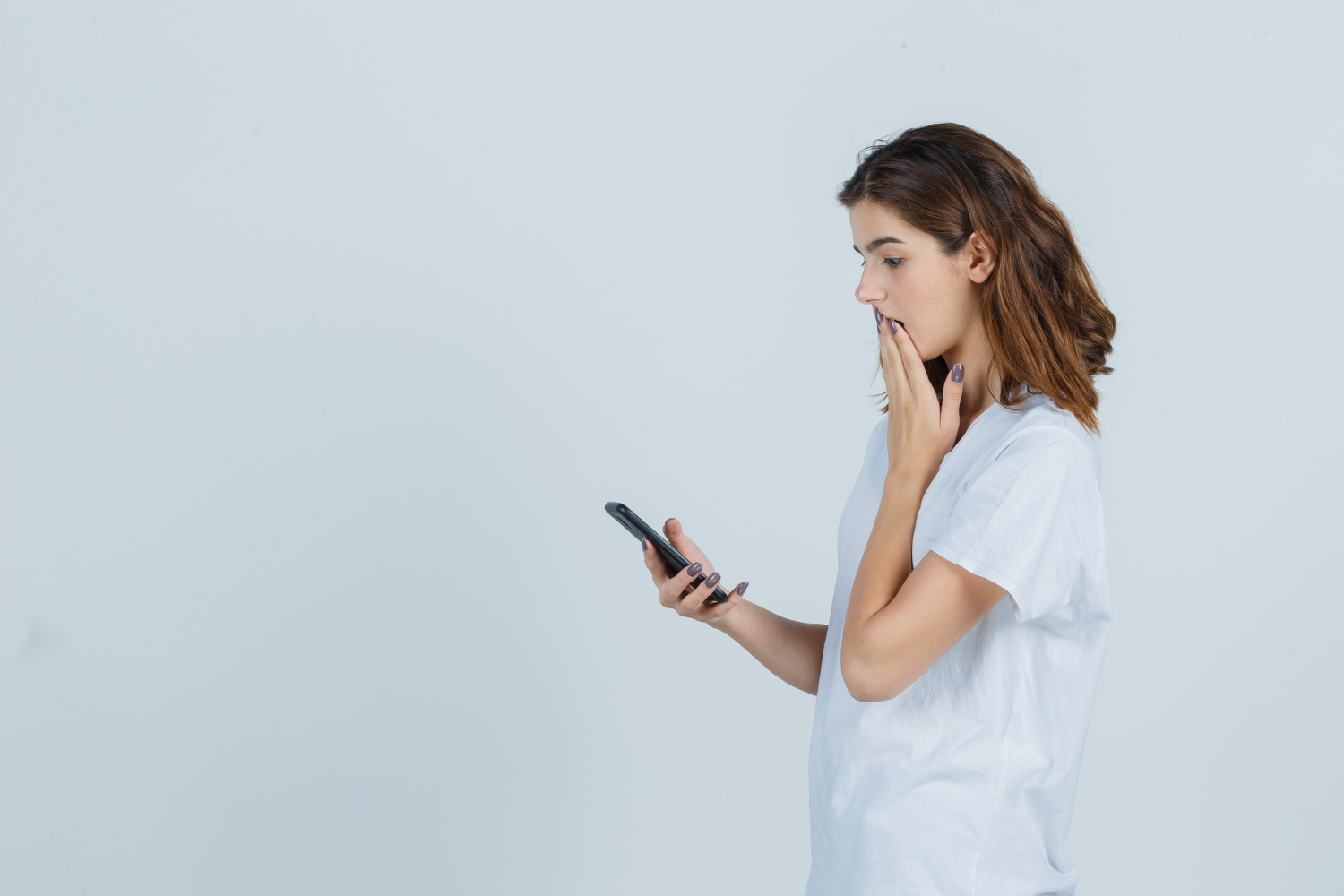 Side view of a woman looking at her phone | Source: Freepik