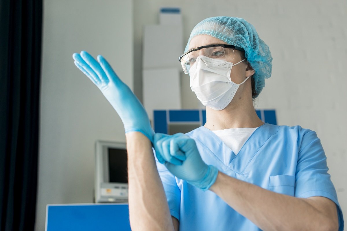 Miembro del personal sanitario se coloca guantes de látex. | Foto: Freepik