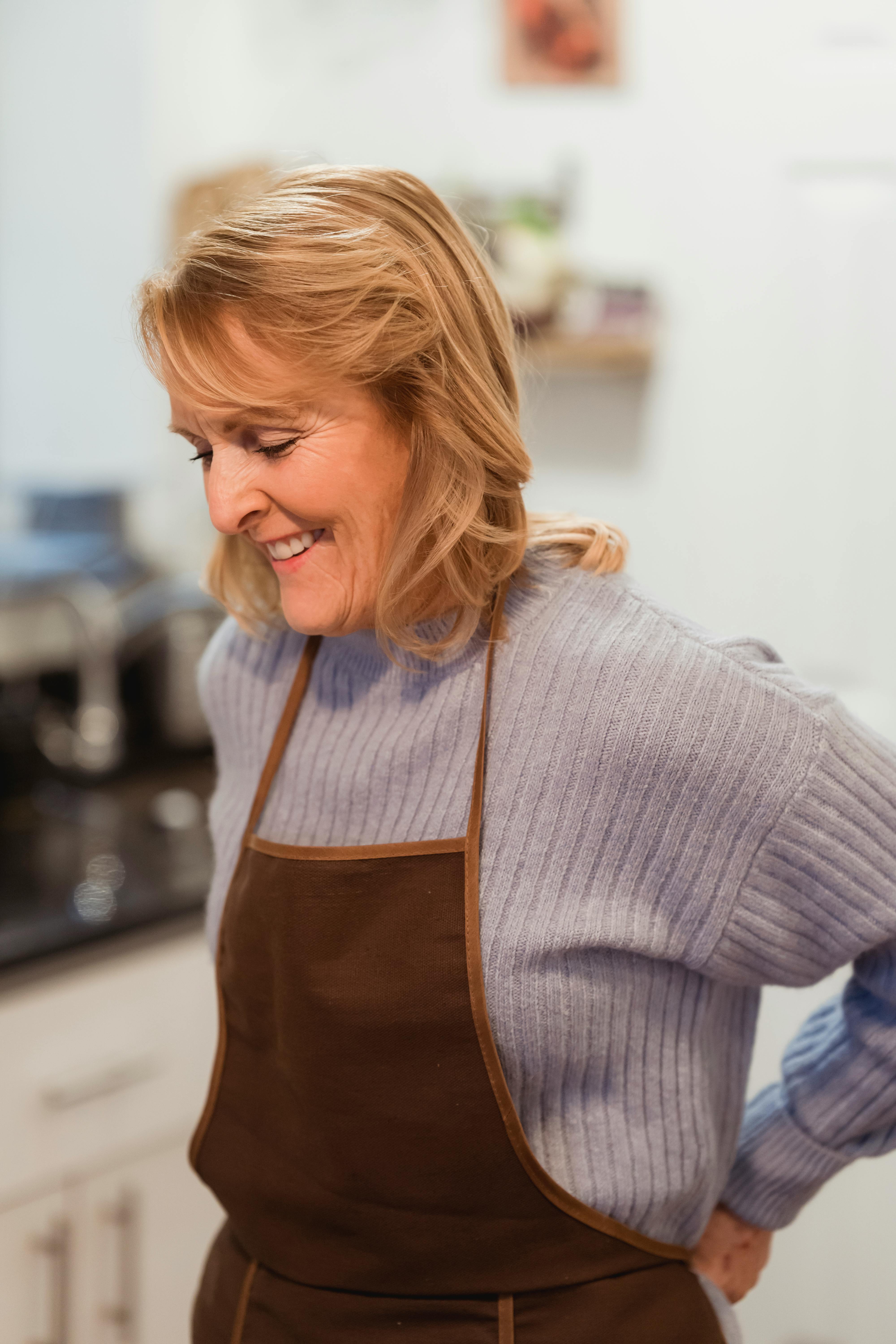 A woman in an apron while standing next to the kitchen counter | Source: Pexels