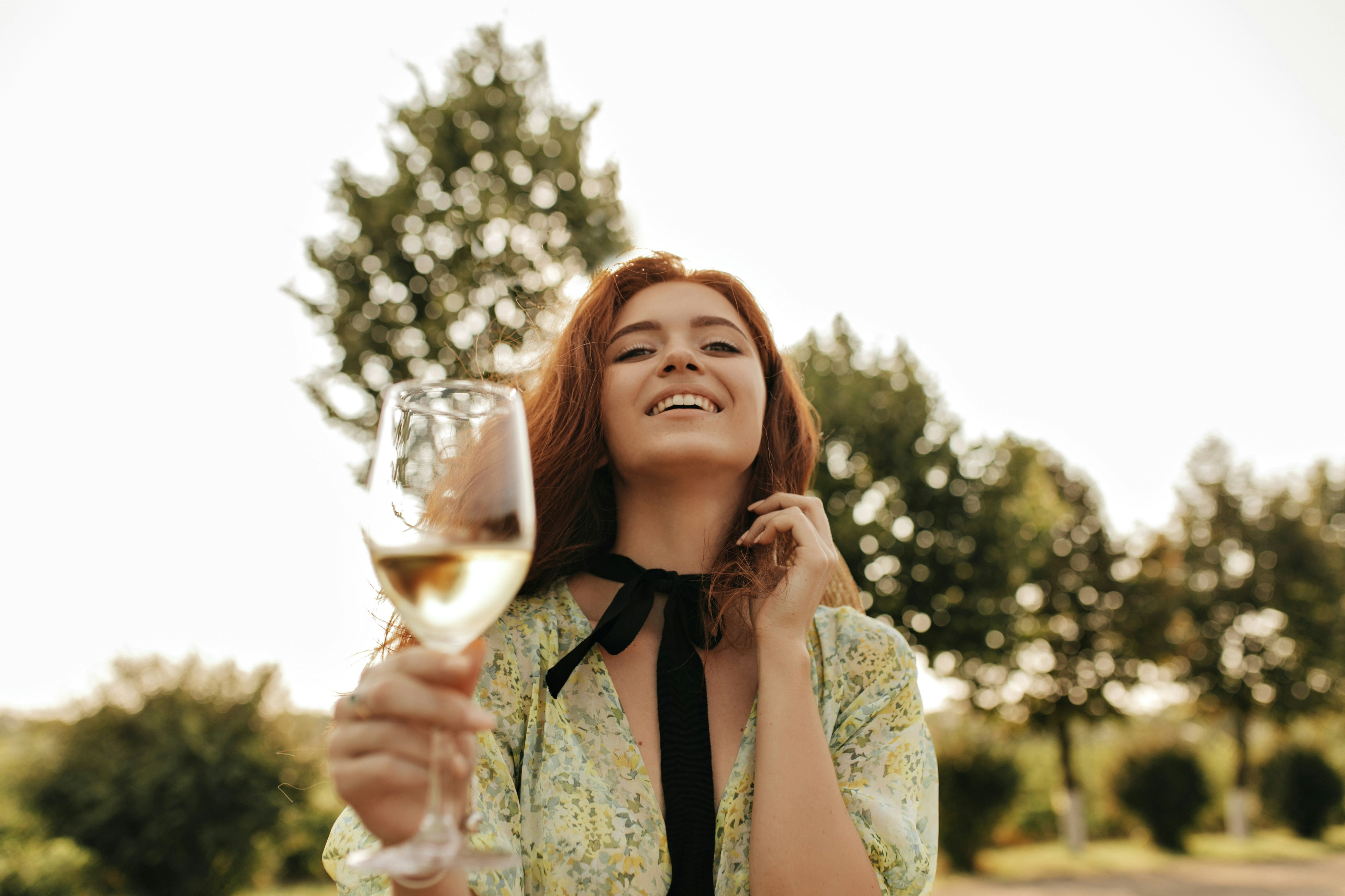 A woman laughing while holding a glass of wine | Source: Unsplash
