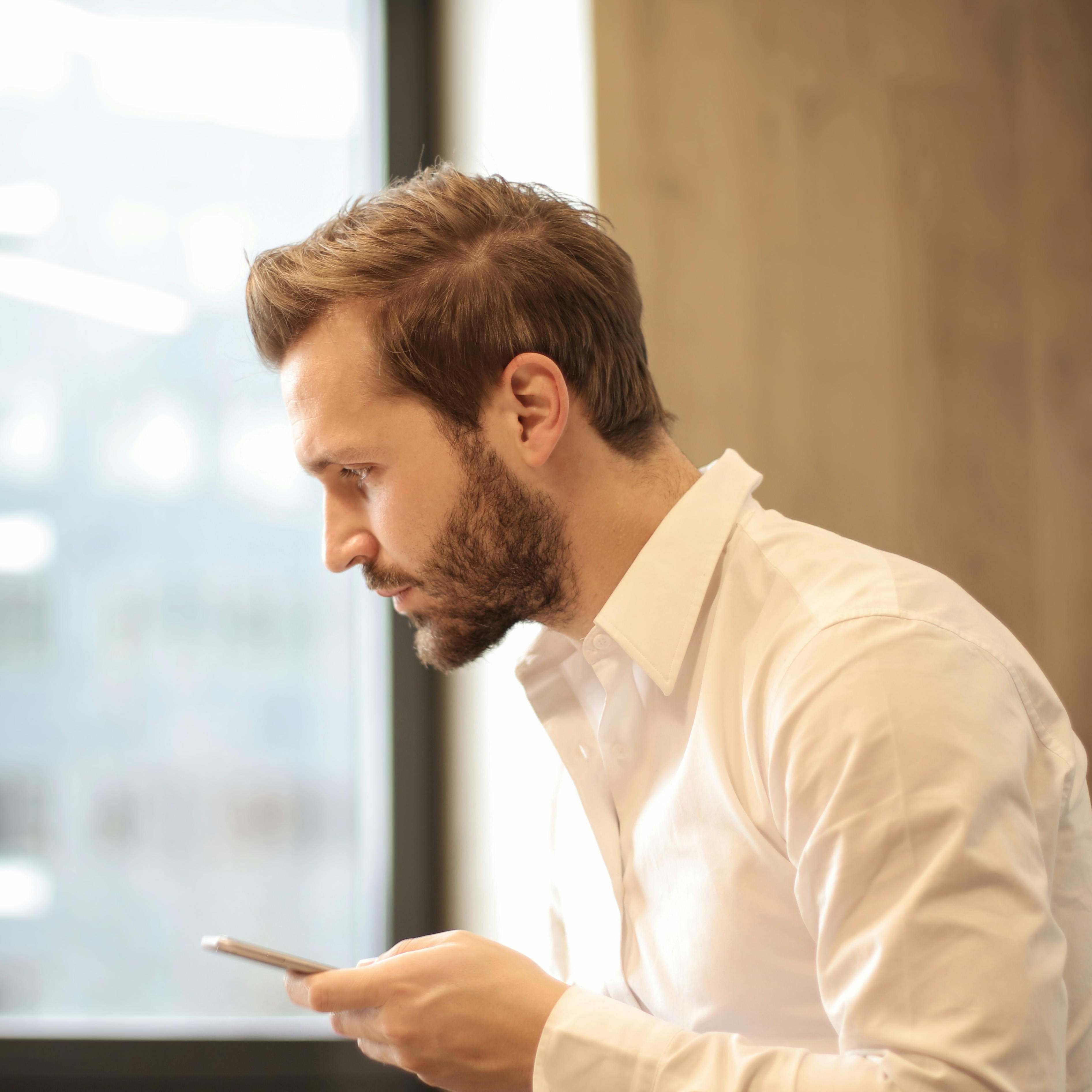 A man holding a phone, looking contemplative | Source: Pexels