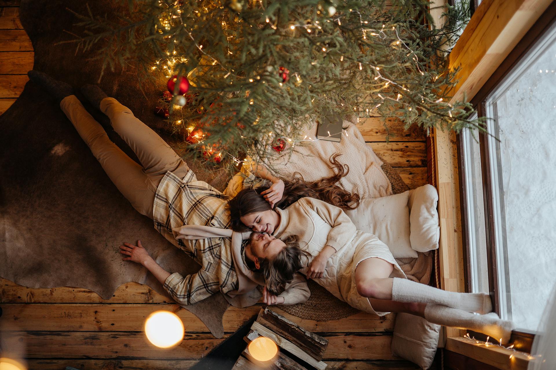 A couple lying down near a Christmas tree | Source: Pexels