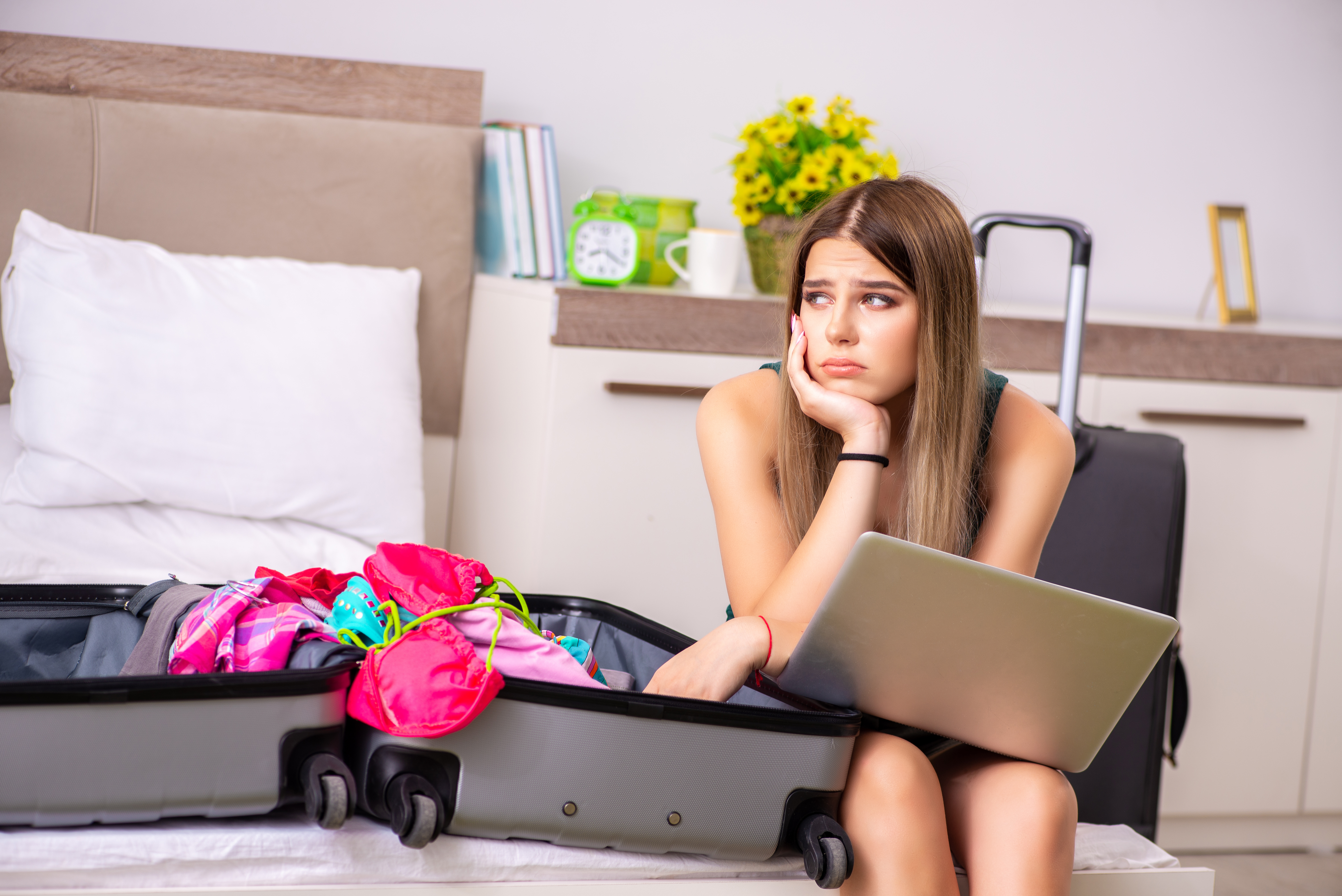 Upset young girl sitting next to a packed suitcase | Source: Shutterstock