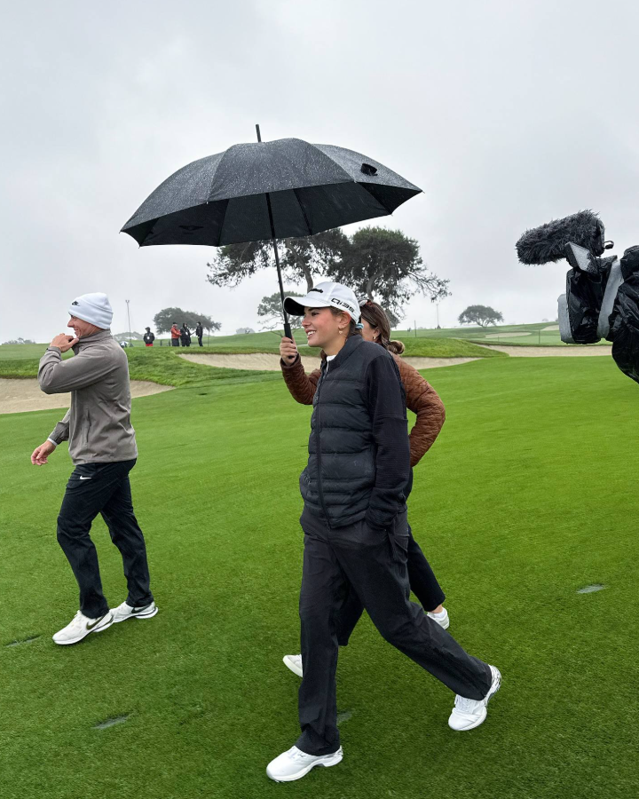 Kai walks the rainy course, smiling as a cameraman captures the moment | Source: Facebook/Kai-Trump