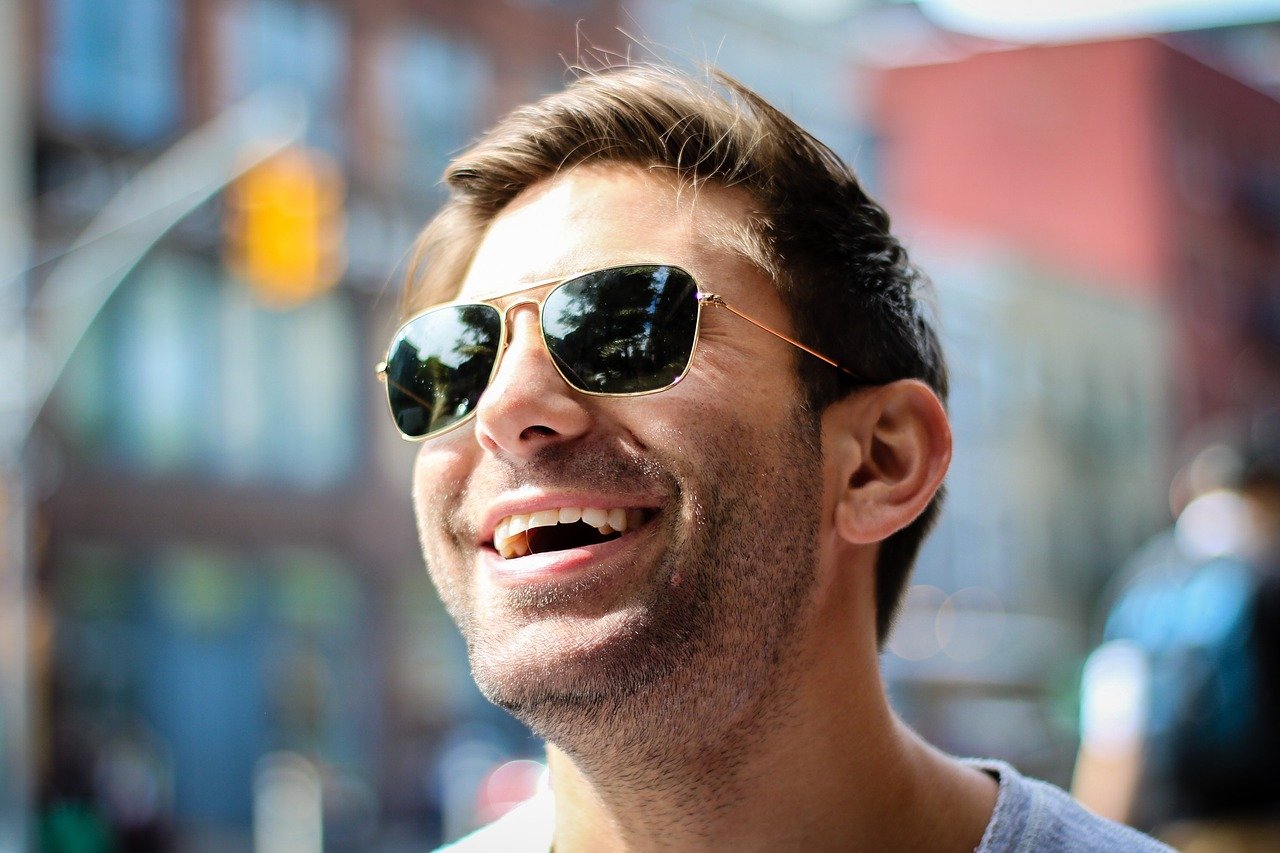 A man wearing sunglasses and laughing while outdoors | Photo: Pixabay/Pexels