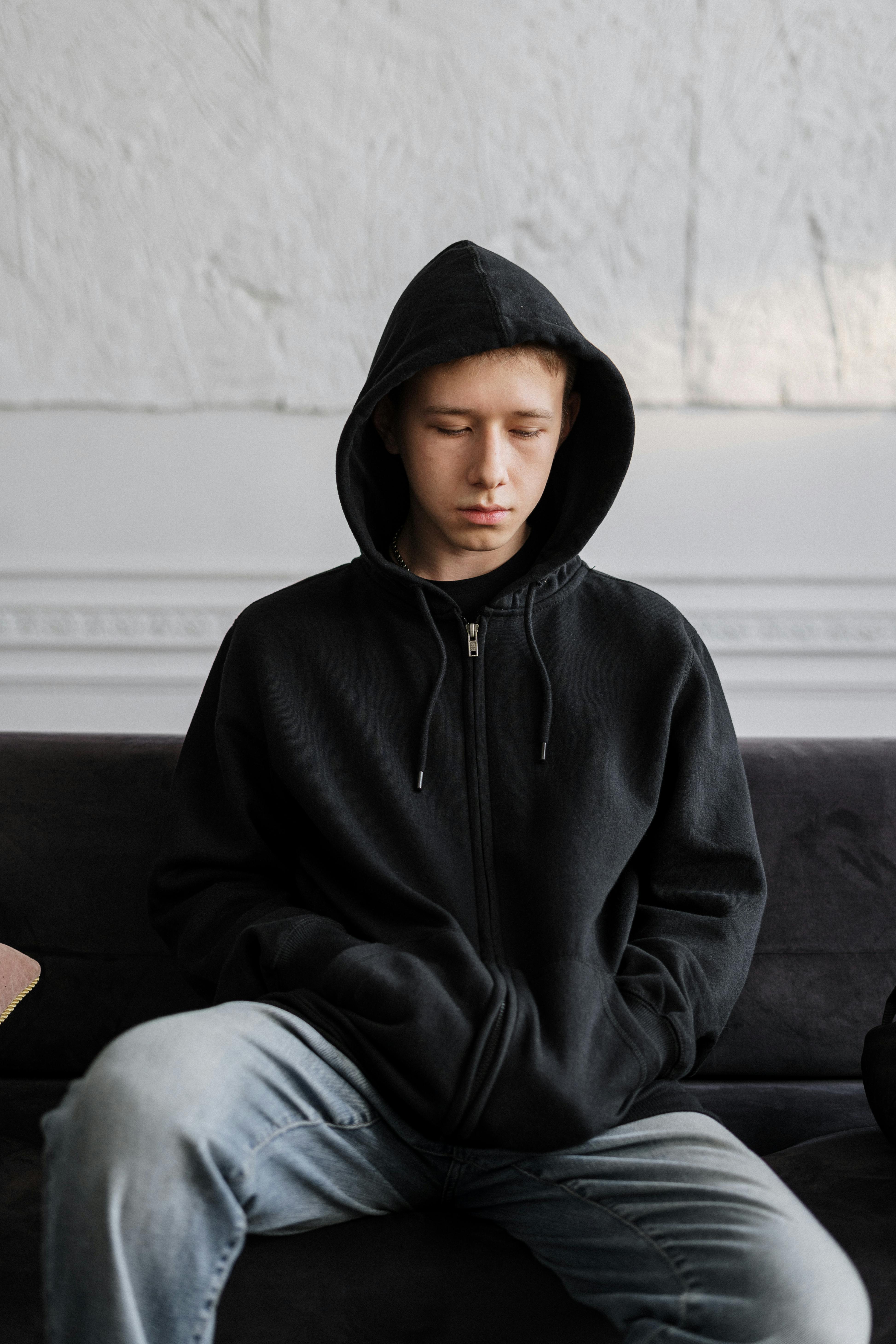 A teenager sitting on a couch while looking down | Source: Pexels