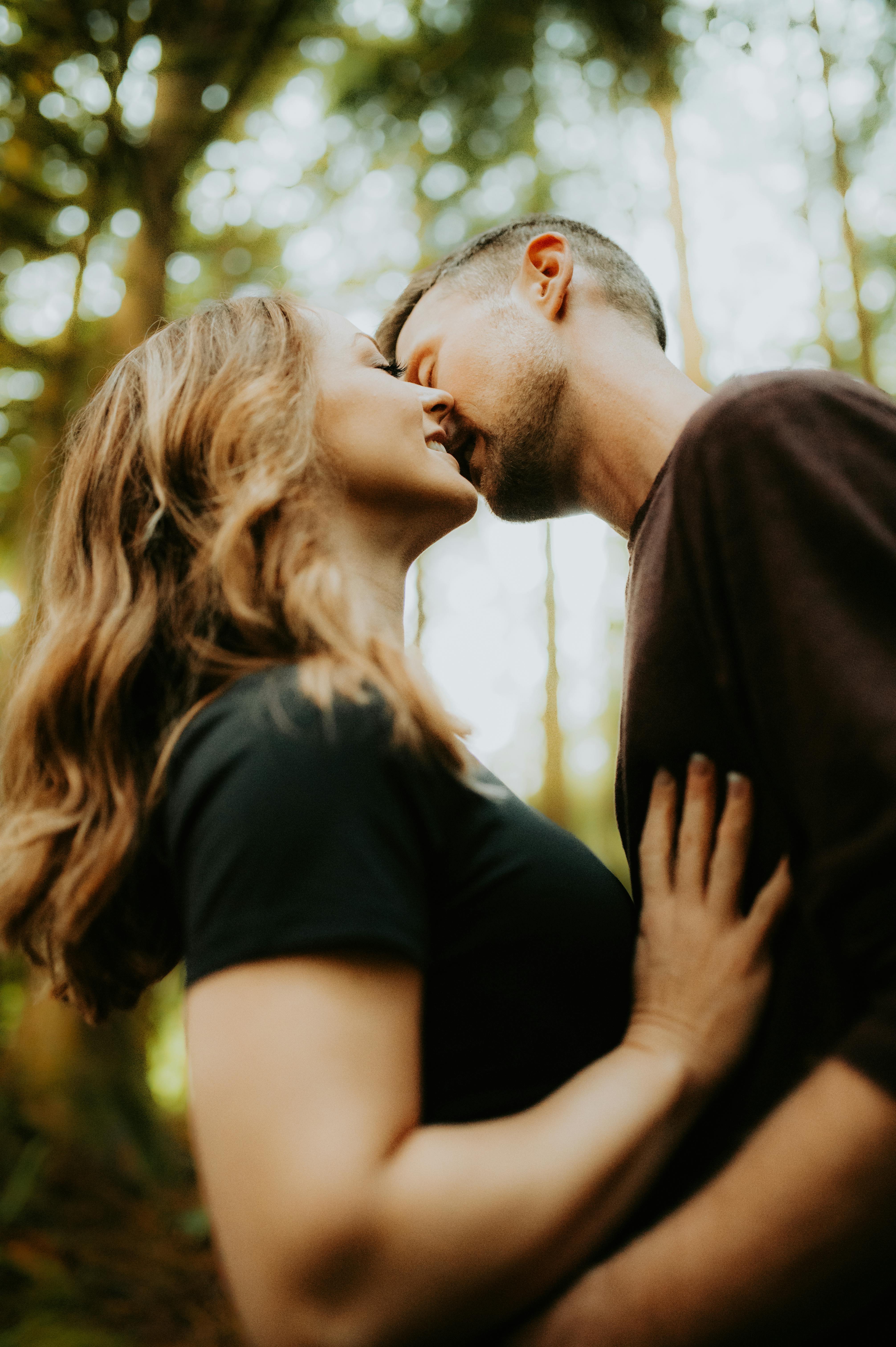 Un hombre besando a una mujer en el bosque | Fuente: Pexels