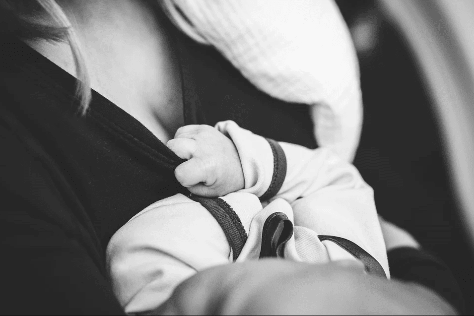 A monochrome portrait of a woman who is about to breast feed her child | Photo: Pixabay