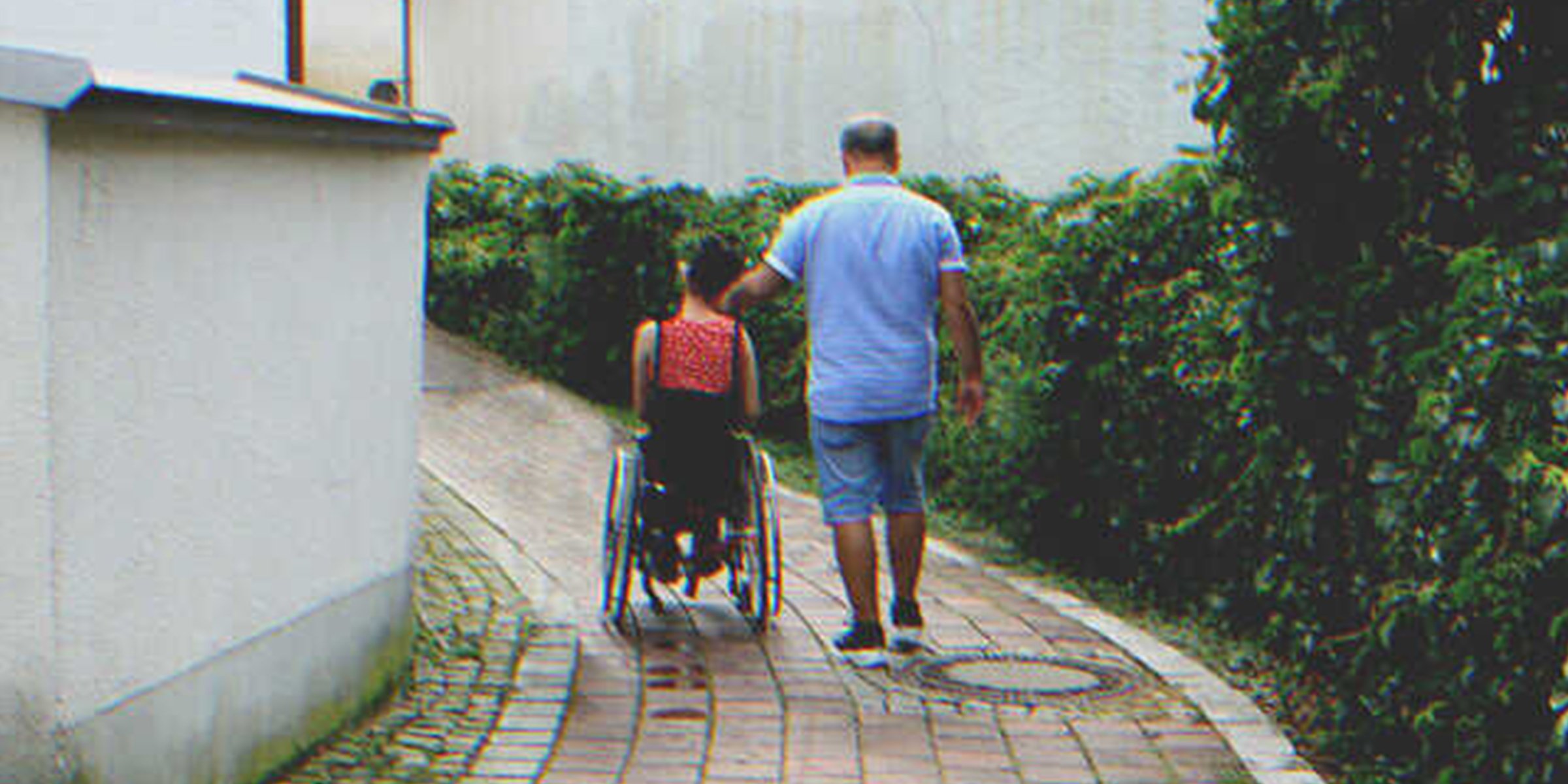 A girl in a wheelchair next to a man | Source: Shutterstock