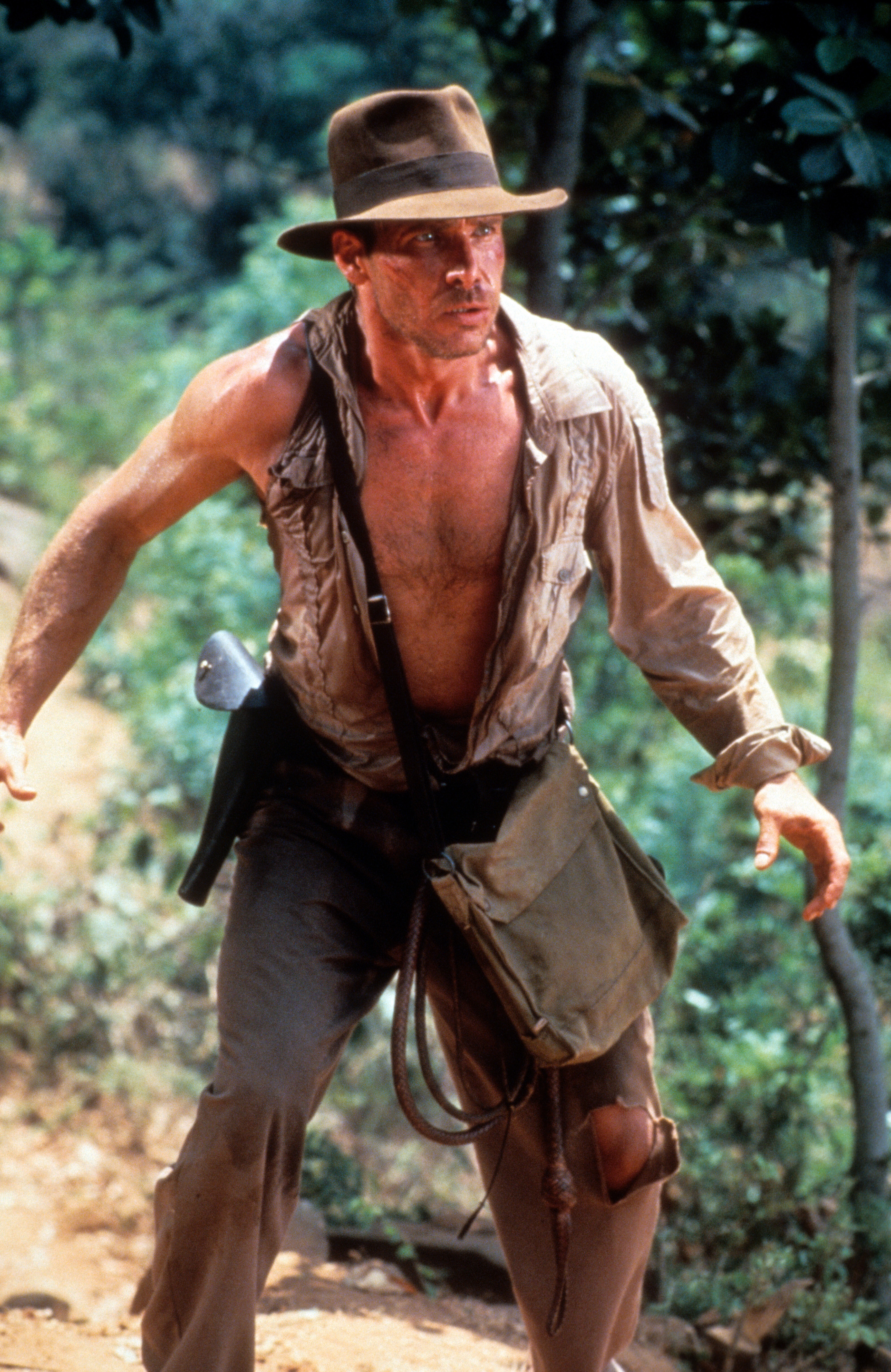 Harrison Ford, rocking his signature fedora, is a true force of nature in "Indiana Jones and the Temple of Doom." He flaunts a ripped physique in a torn, sweat-stained shirt, showing off the muscles he carefully sculpted for the role. | Source: Getty Images