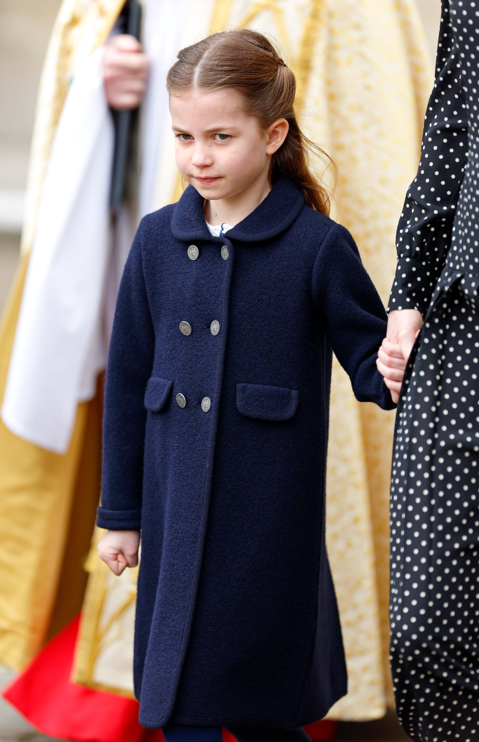 A composed seven-year-old Charlotte, in a double-breasted navy coat with silver buttons, holds Catherine's hand outside Westminster Abbey during the Service of Thanksgiving for Prince Philip in March 2022.