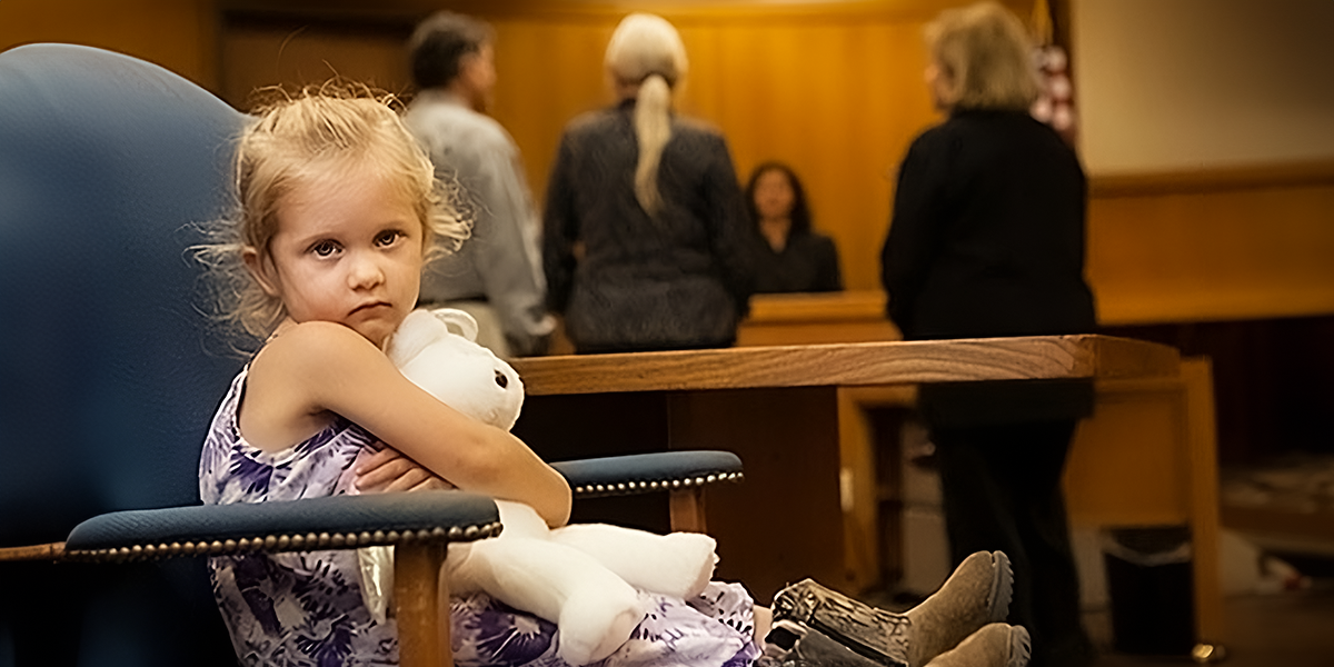 Girl sits with a toy in a courtroom | Source: Shutterstock
