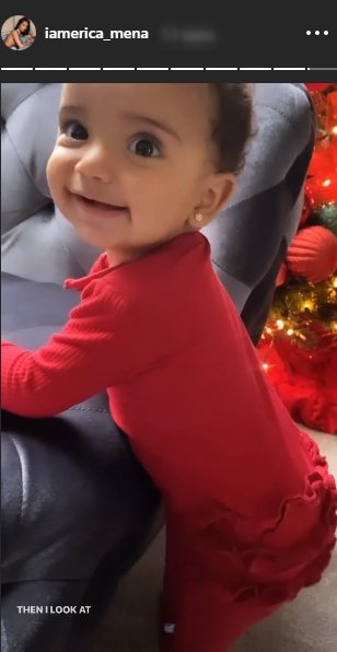 “Love & Hip Hop” star Erica Mena’s daughter, Safire, wearing a red dress and resting on a couch. | Photo: Instagram/iamerica_mena