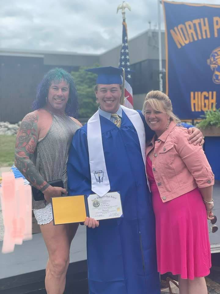 Aidan Dorgan poses at his high school graduation ceremony alongside Robert Dorgan, also known as Roberto Esposito, and Rhonda Dorgan | Source: Facebook/roberta.esposito.78490