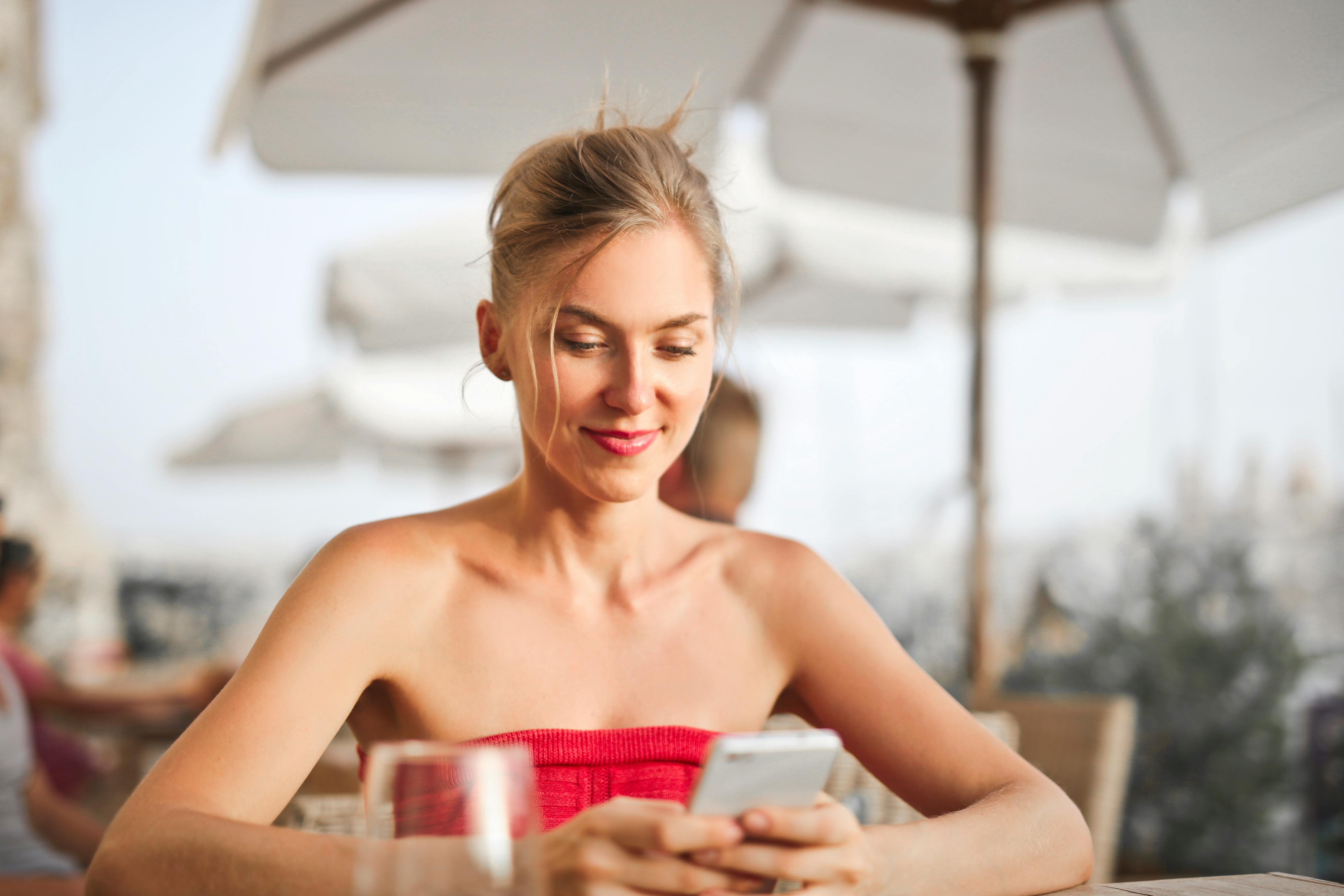 A woman smiling while looking at her phone | Source: Pexels