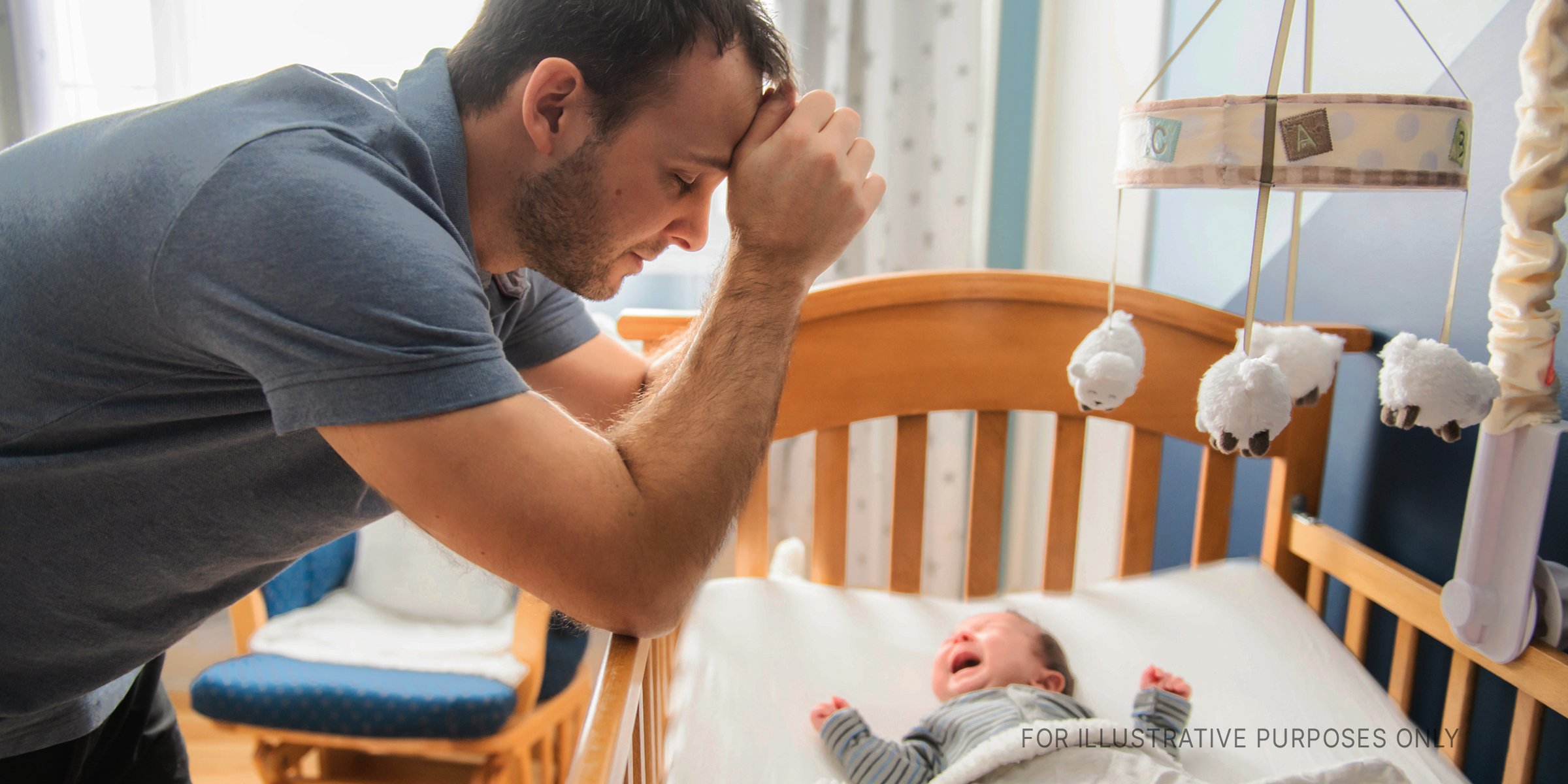 Man overlooking a baby in a crib. | Source: Shutterstock