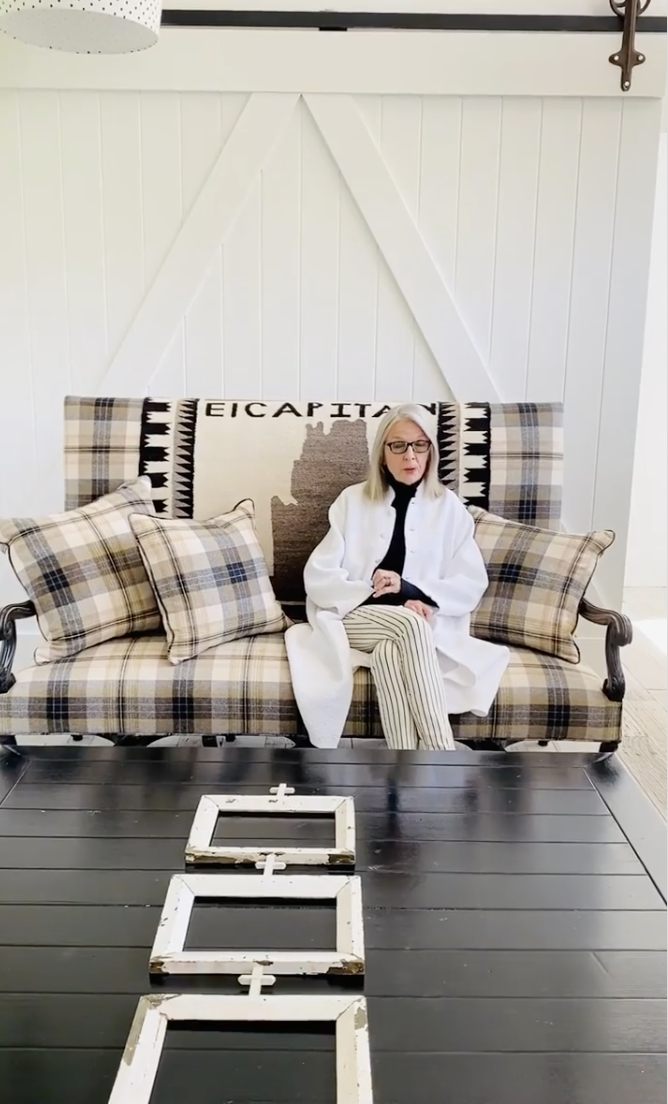 Diane Keaton pictured seated on a plaid settee in front of barn-style doors inside her Sullivan Canyon home, dated July 30, 2020 | Source: Instagram/diane_keaton