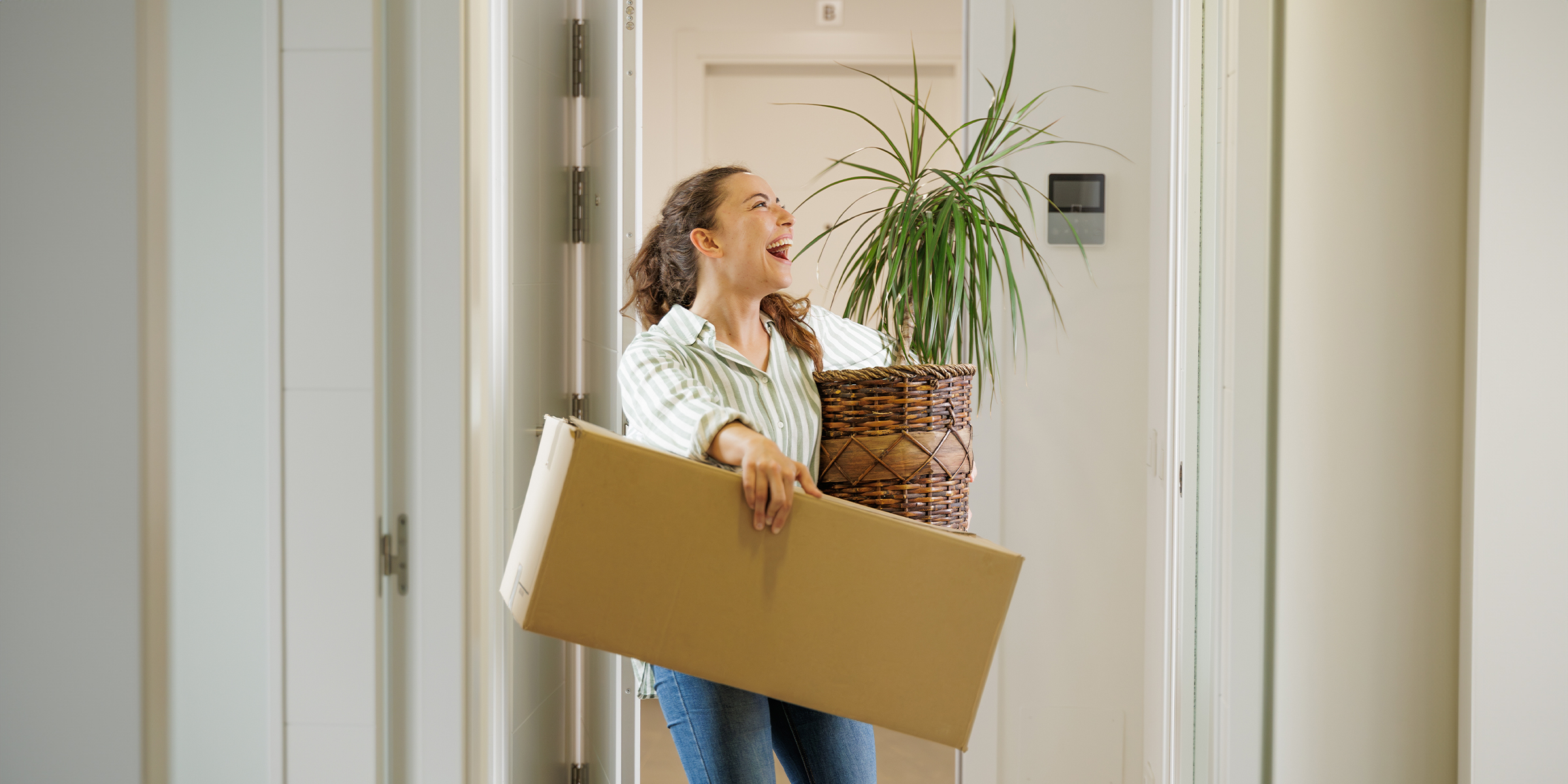 A woman carrying a box and plant | Source: Shutterstock