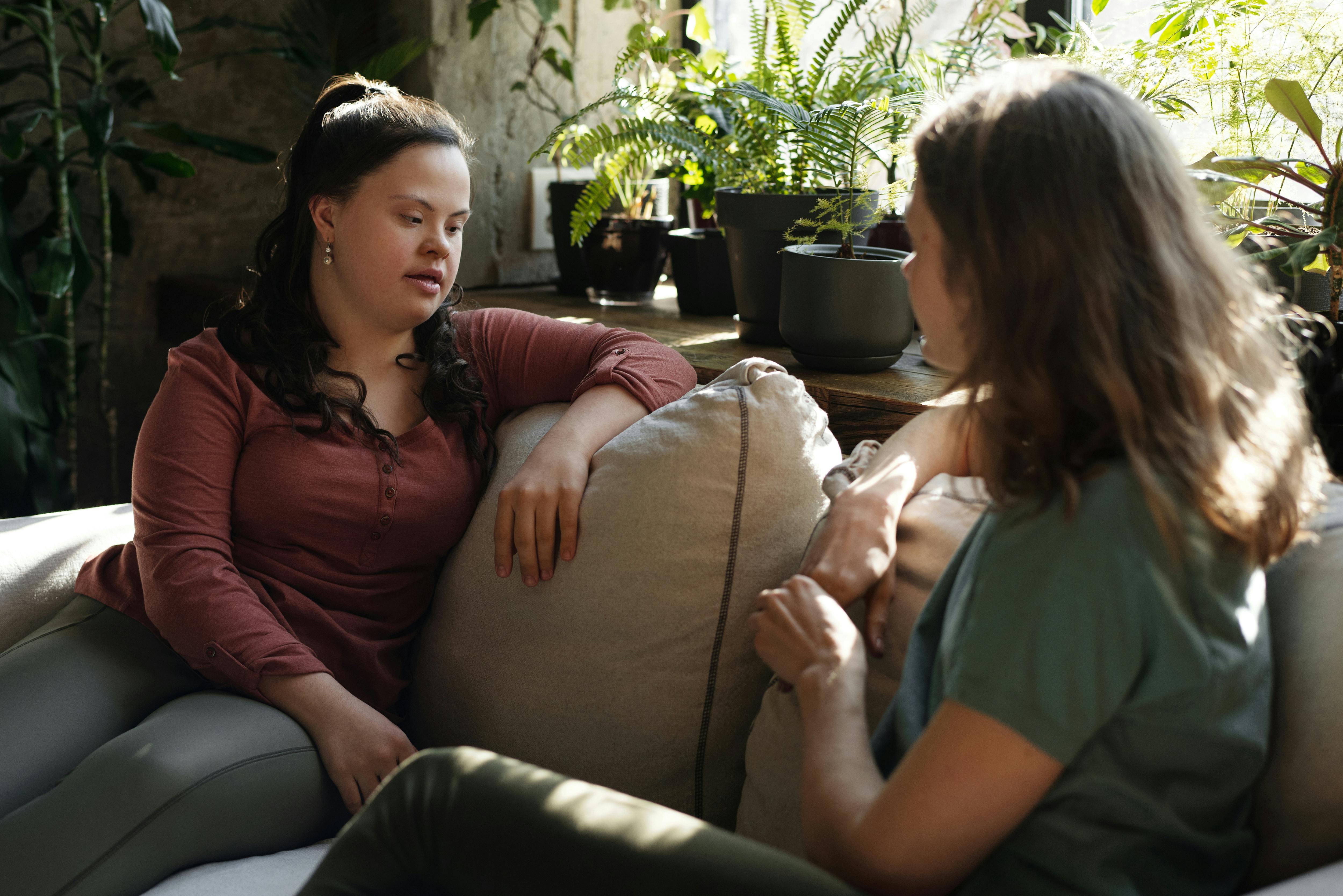 Two women sitting on a couch talking  | Source: Pexels