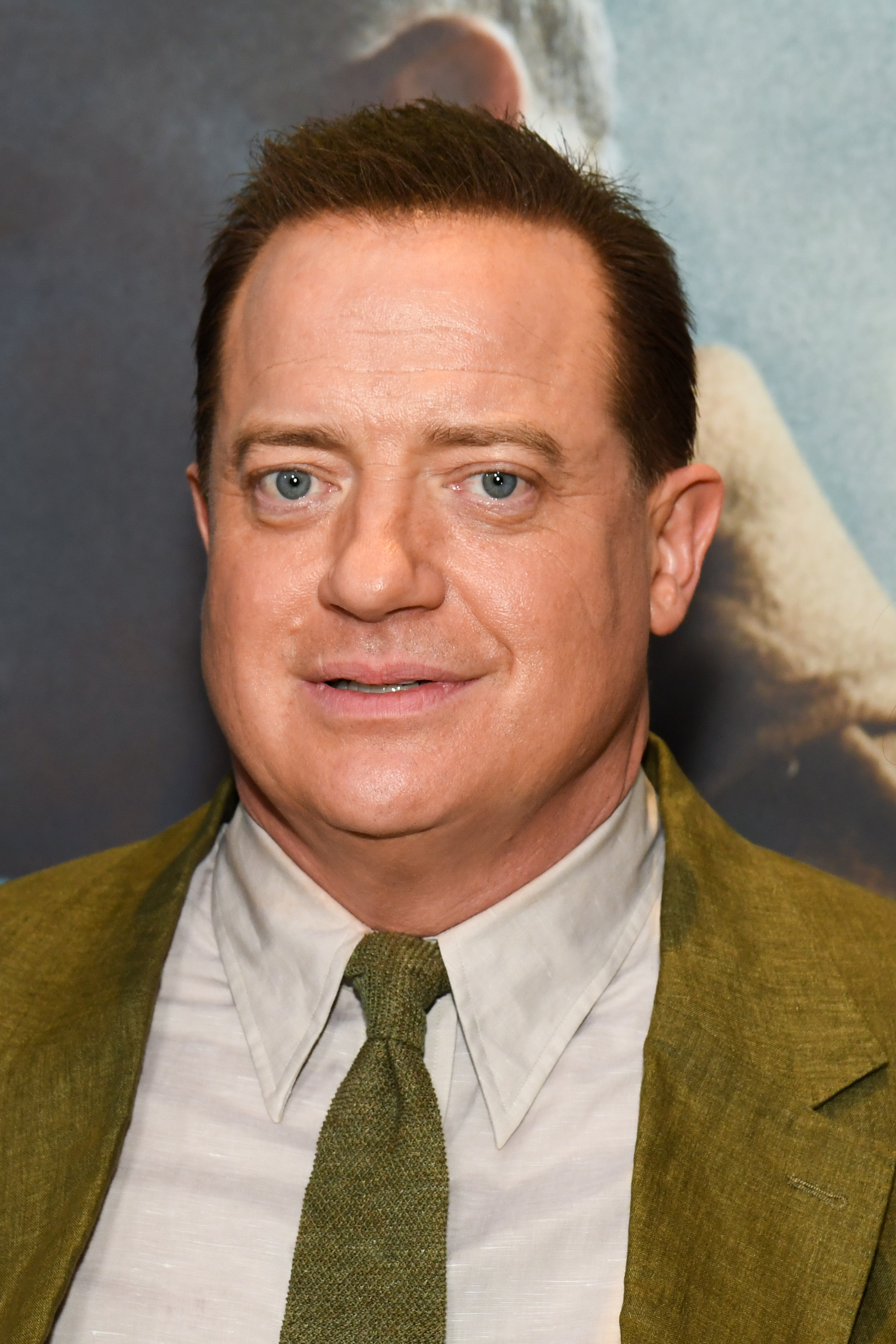 Brendan Fraser appears in a close-up wearing an olive suit, matching tie, and gray shirt at the New York premiere of "Pressure," held at AMC Lincoln Square 13.