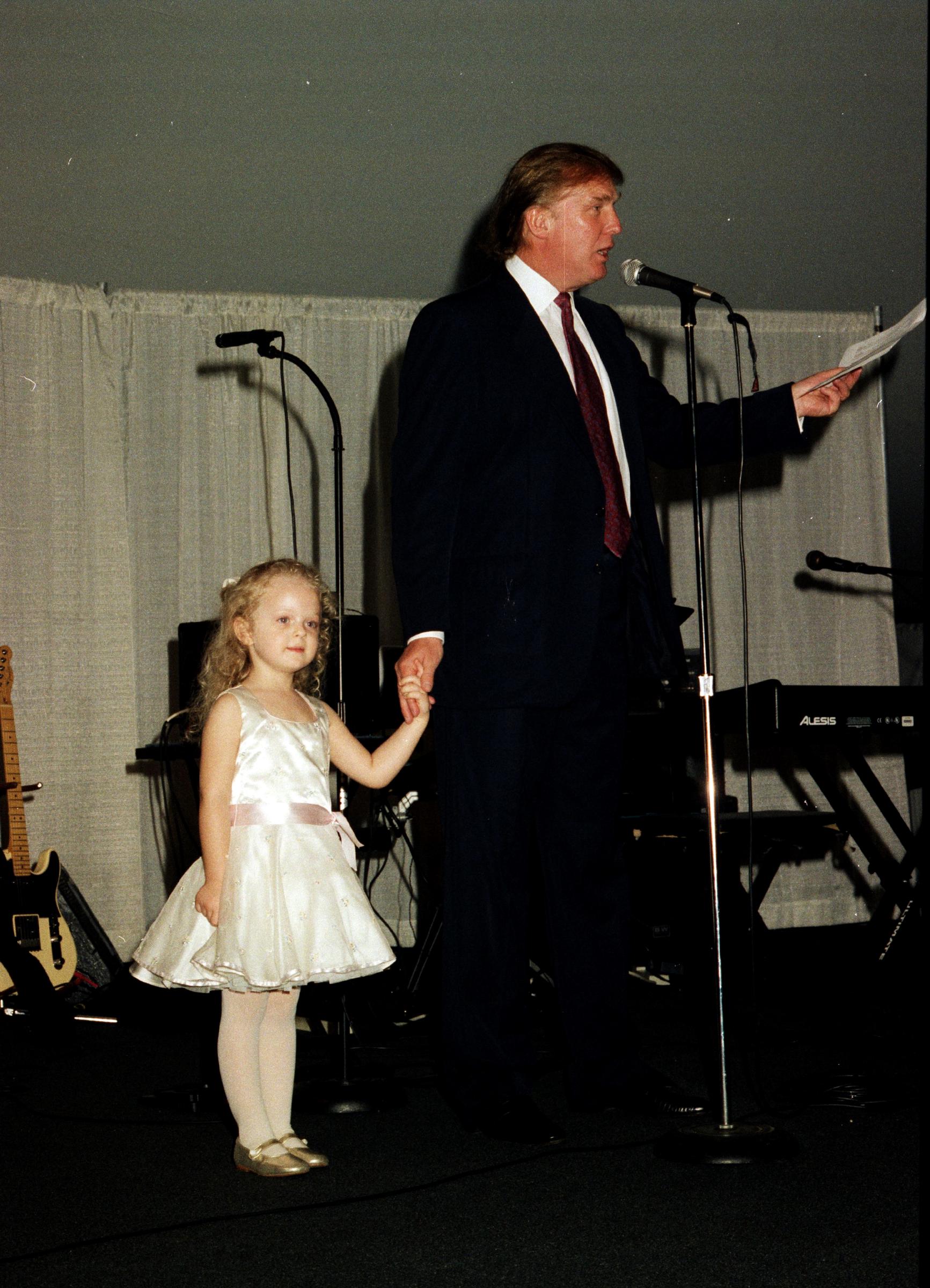 Donald Trump holding hands with his daughter while speaking onstage at the Mar-a-Lago club, in Palm Beach, Florida, on February 22, 1997. | Source: Getty Images