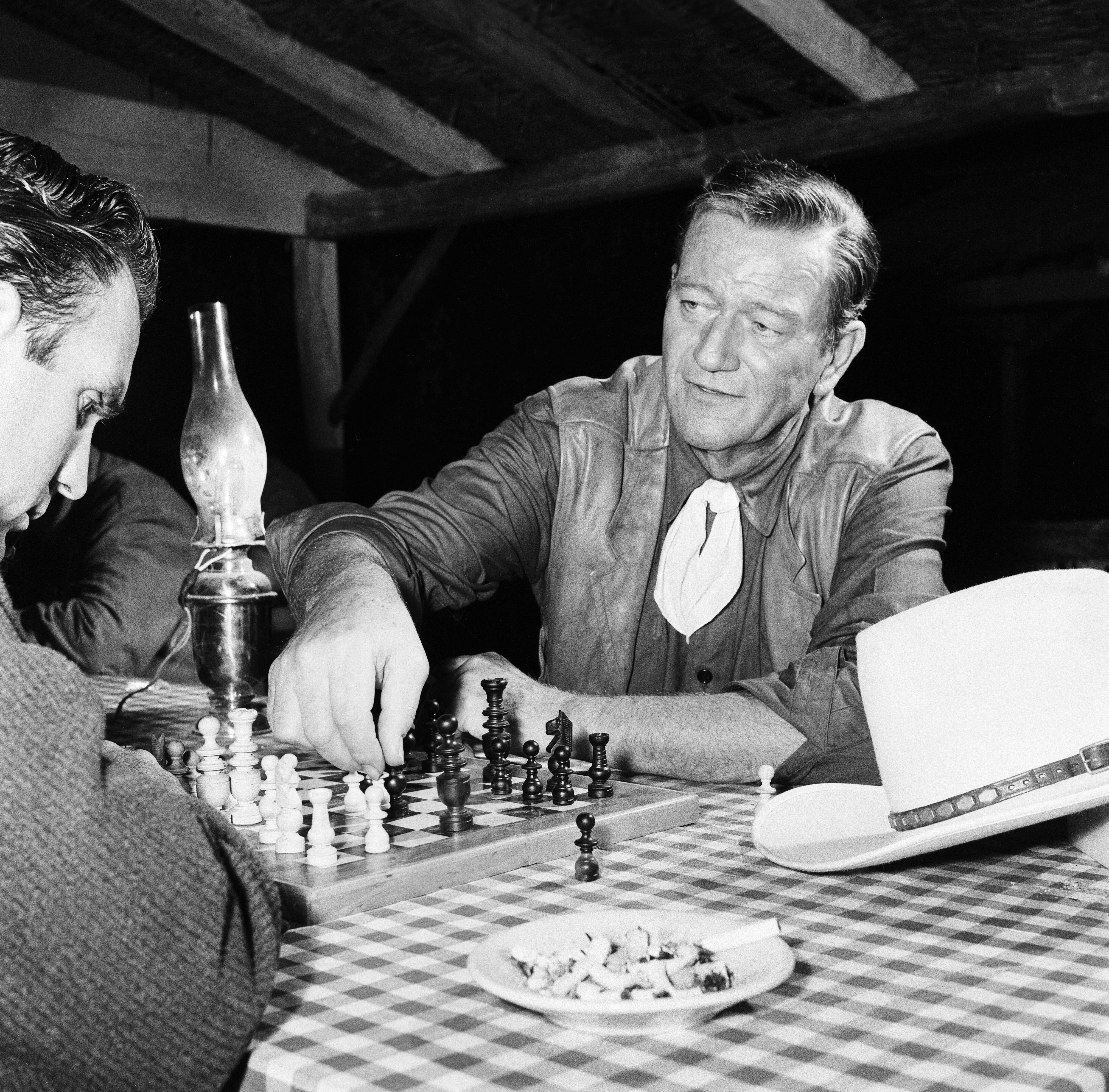 John Wayne on the set of the film "Circus World" at the Bronston Film Studios enjoying a game of chess between shots in 1963 in Madrid, Spain | Photo: Arthur Sidey/Mirrorpix/Mirrorpix via Getty Images