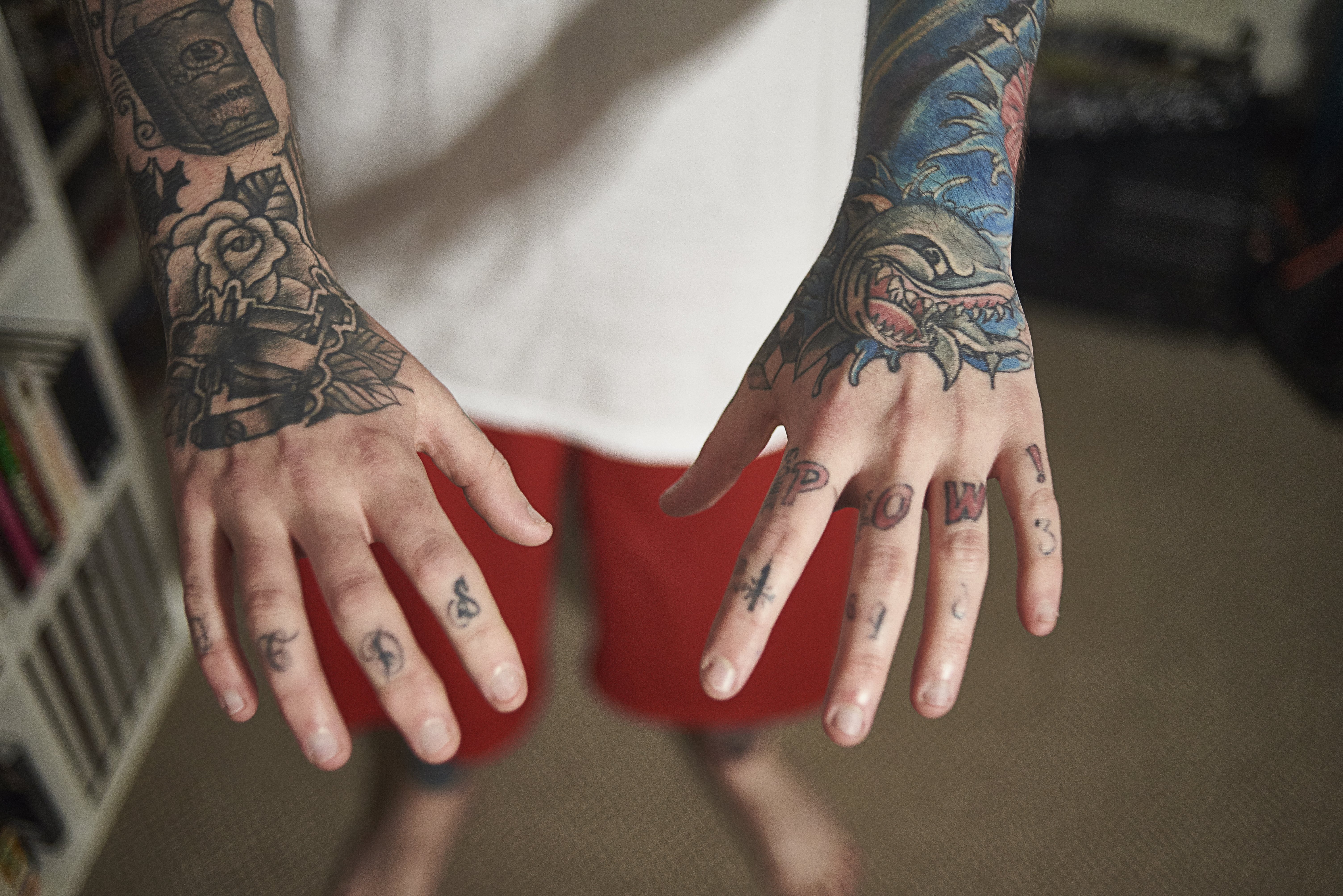 A close up image of a tattoo enthusiast holding out his hands to show the art work he has on his hands. | Source: Getty Images