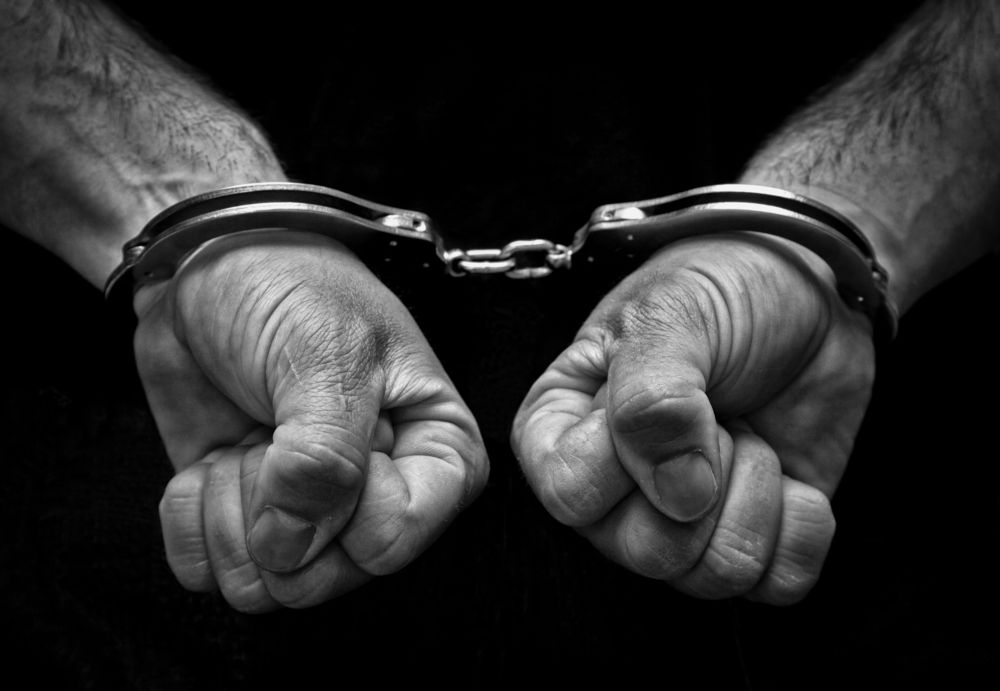 A man's hands in handcuffs. | Source: Shutterstock