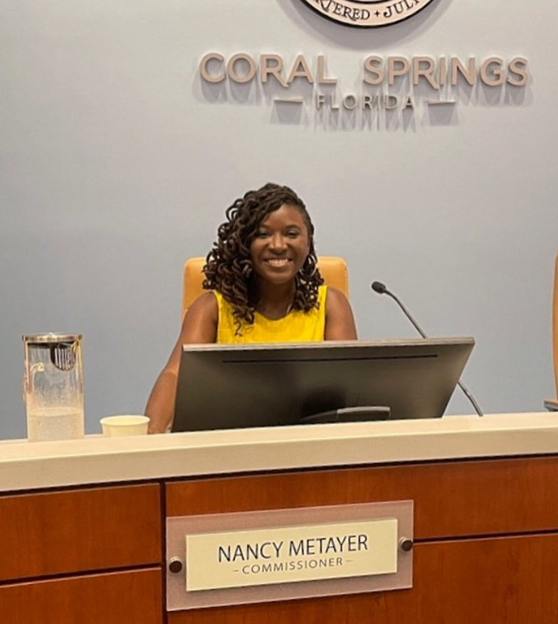 Seated behind the dais in Coral Springs, Nancy Metayer Bowen smiles warmly, her nameplate marking her role as commissioner — an image of leadership grounded in service. | Source: Instagram/nancymetayerbowen