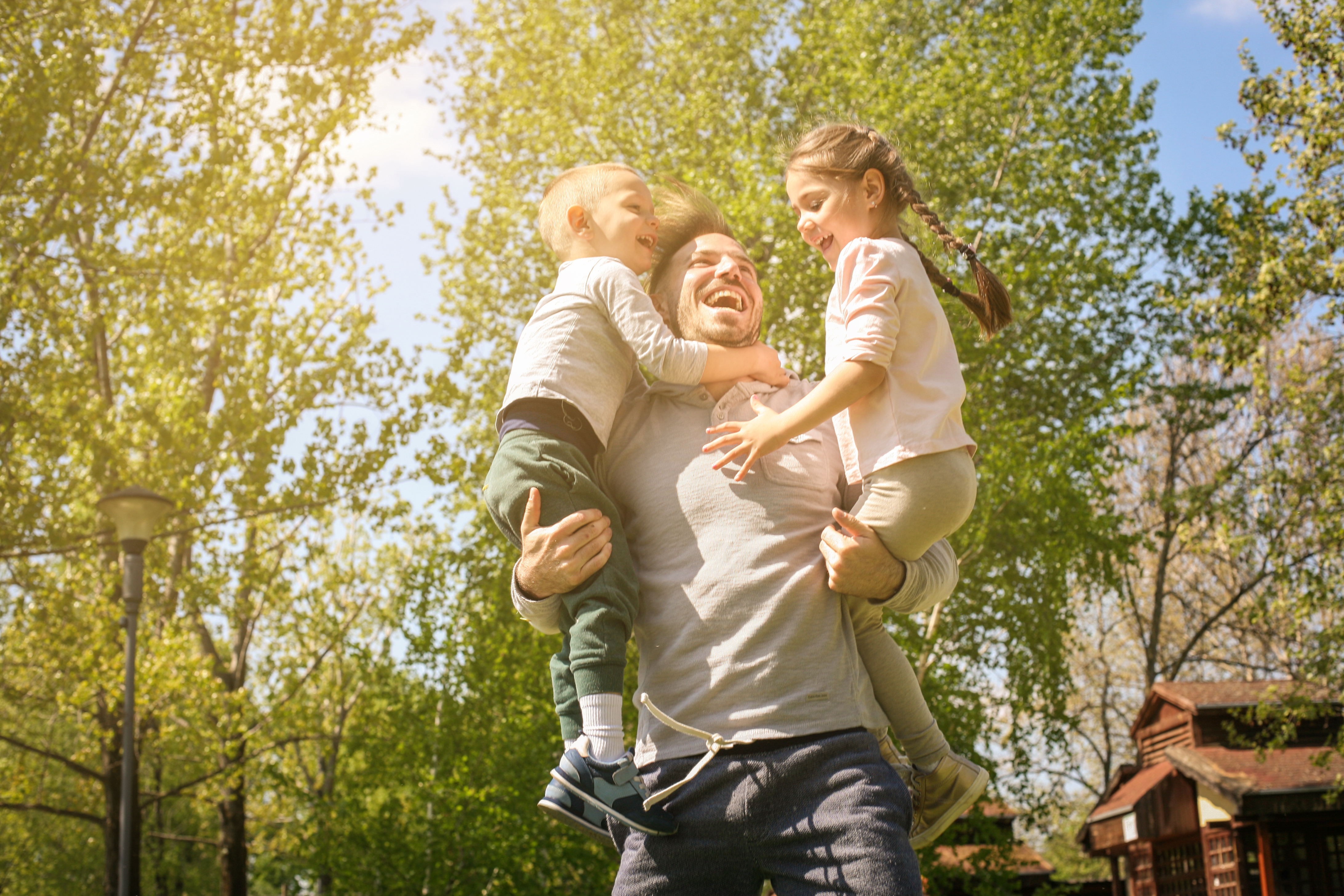 A cheerful father playing with his children in the meadow | Source: Shutterstock