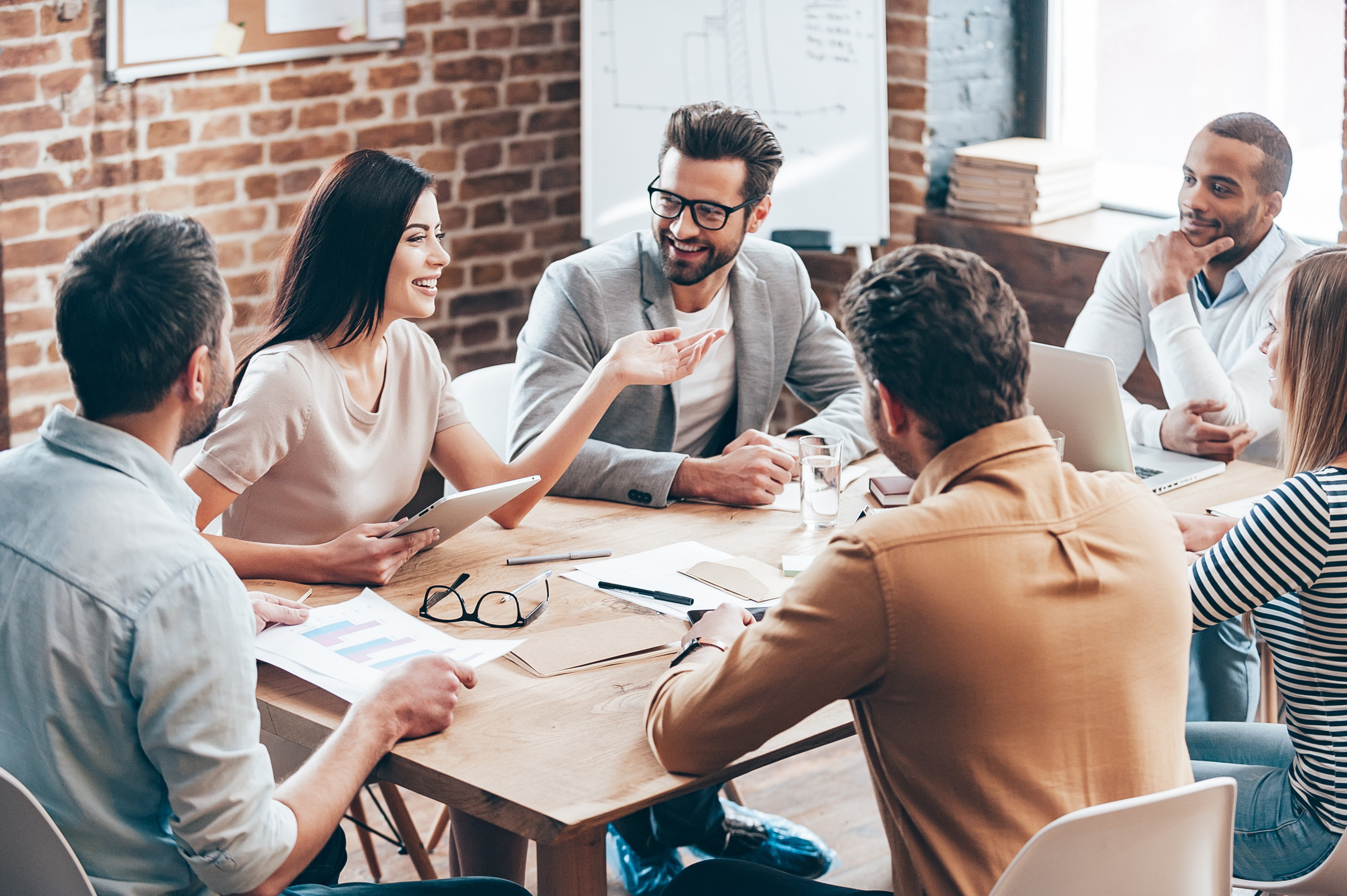 A group over people are sitting around a table having a meeting. | Photo: Shutterstock 