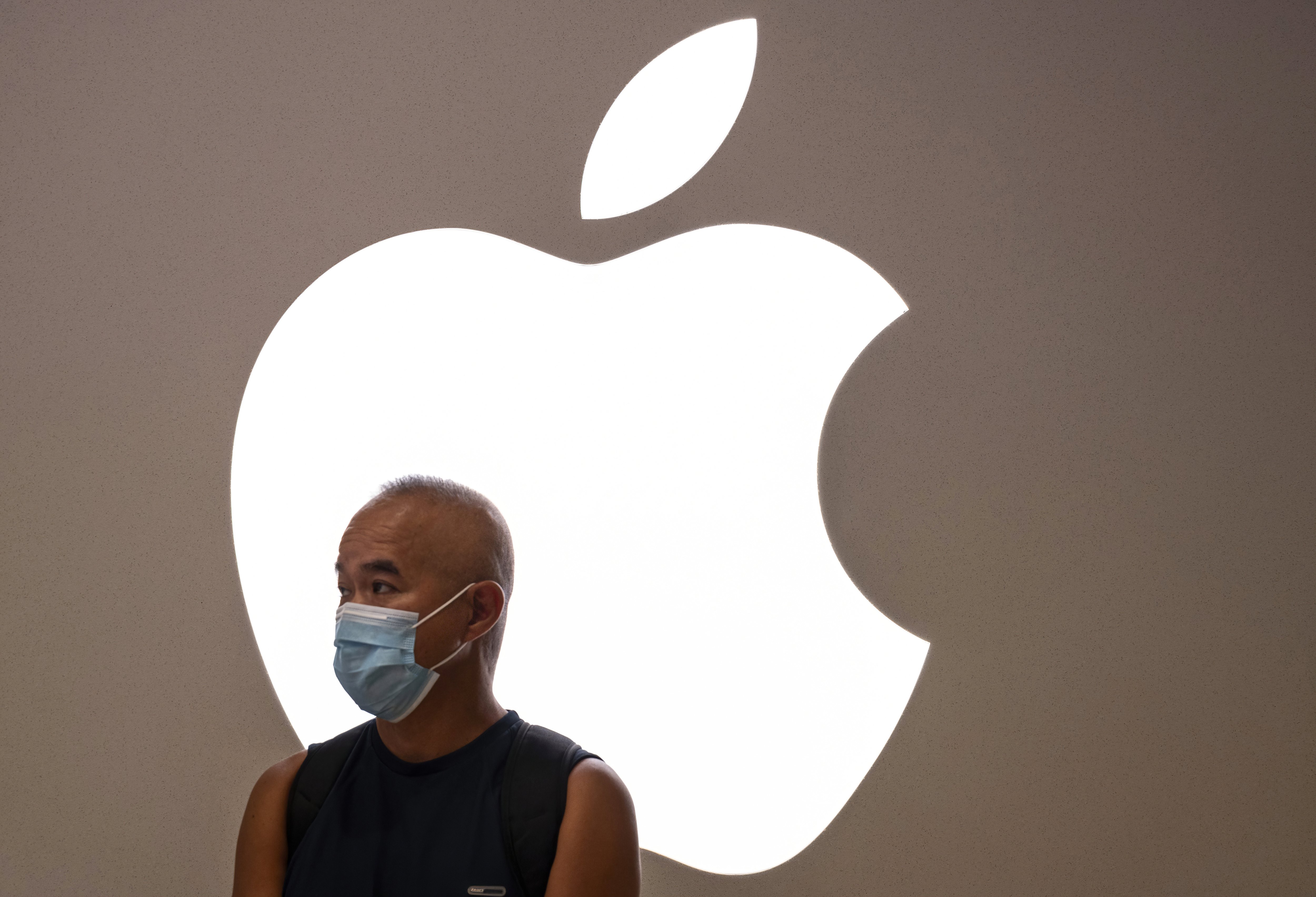 Un homme portant un masque facial est vu devant le logo et le magasin de la firme Apple à Hong Kong. |Photo : Getty Images