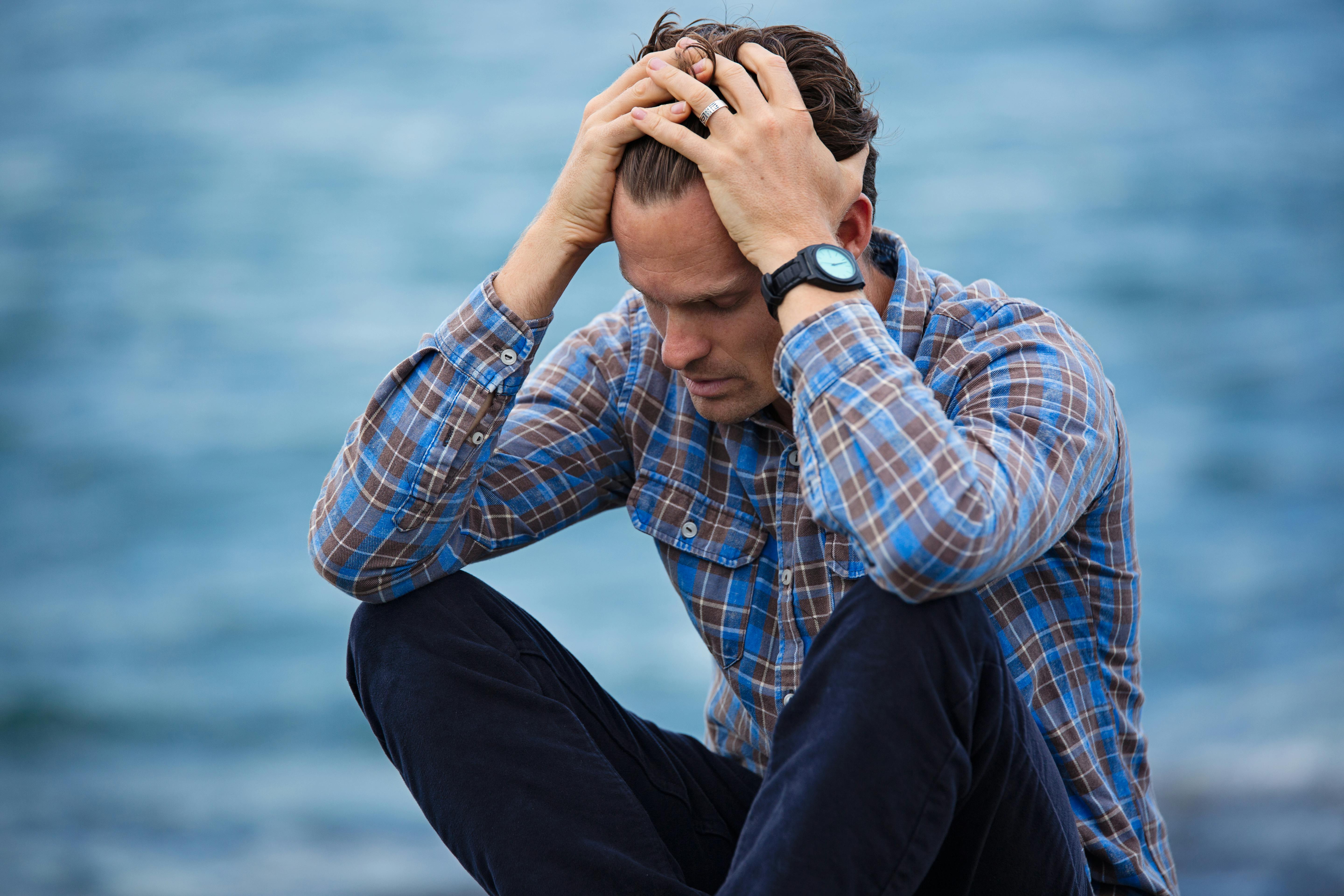 An upset man with his head in his hands | Source: Pexels