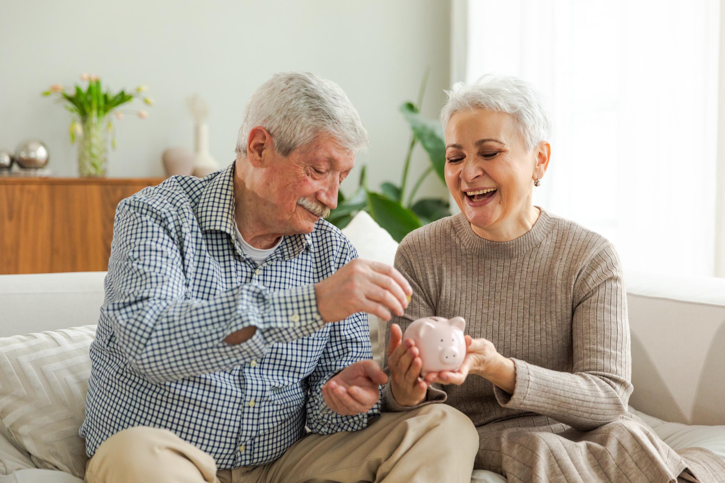A senior couple saving money in a piggy bank | Source: Shutterstock