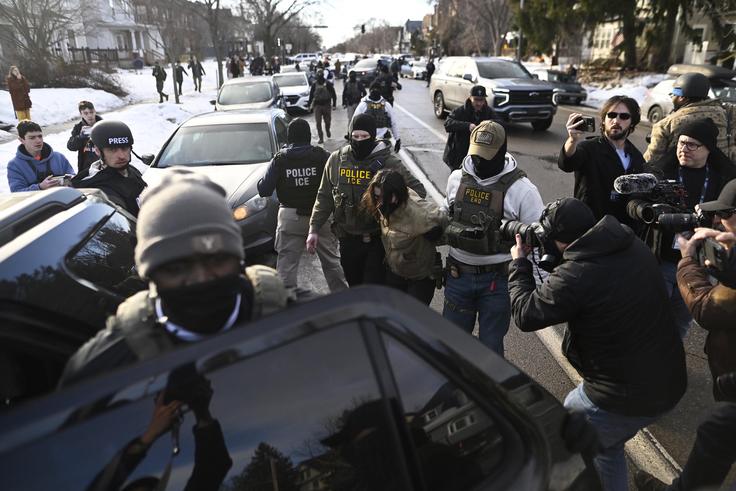 An observer is detained by ICE agents after they arrested two people from a residence on January 13, 2026 in Minneapolis, Minnesota. | Source: Getty Images