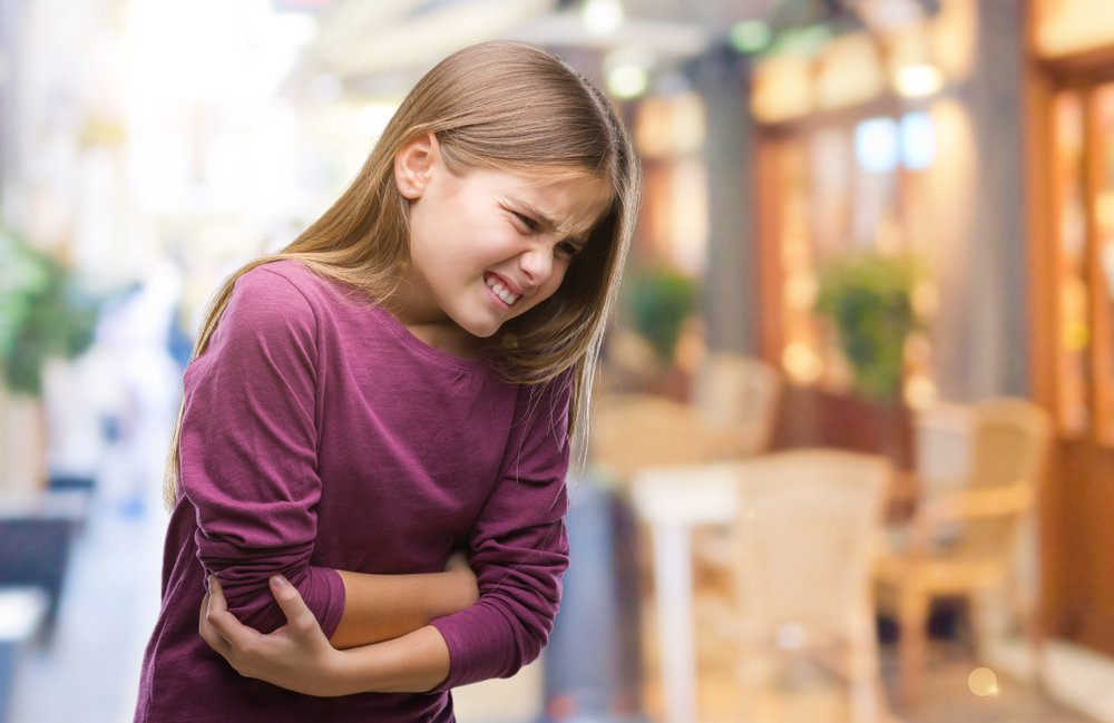Young girl feeling nausea and in pain | Shutterstock